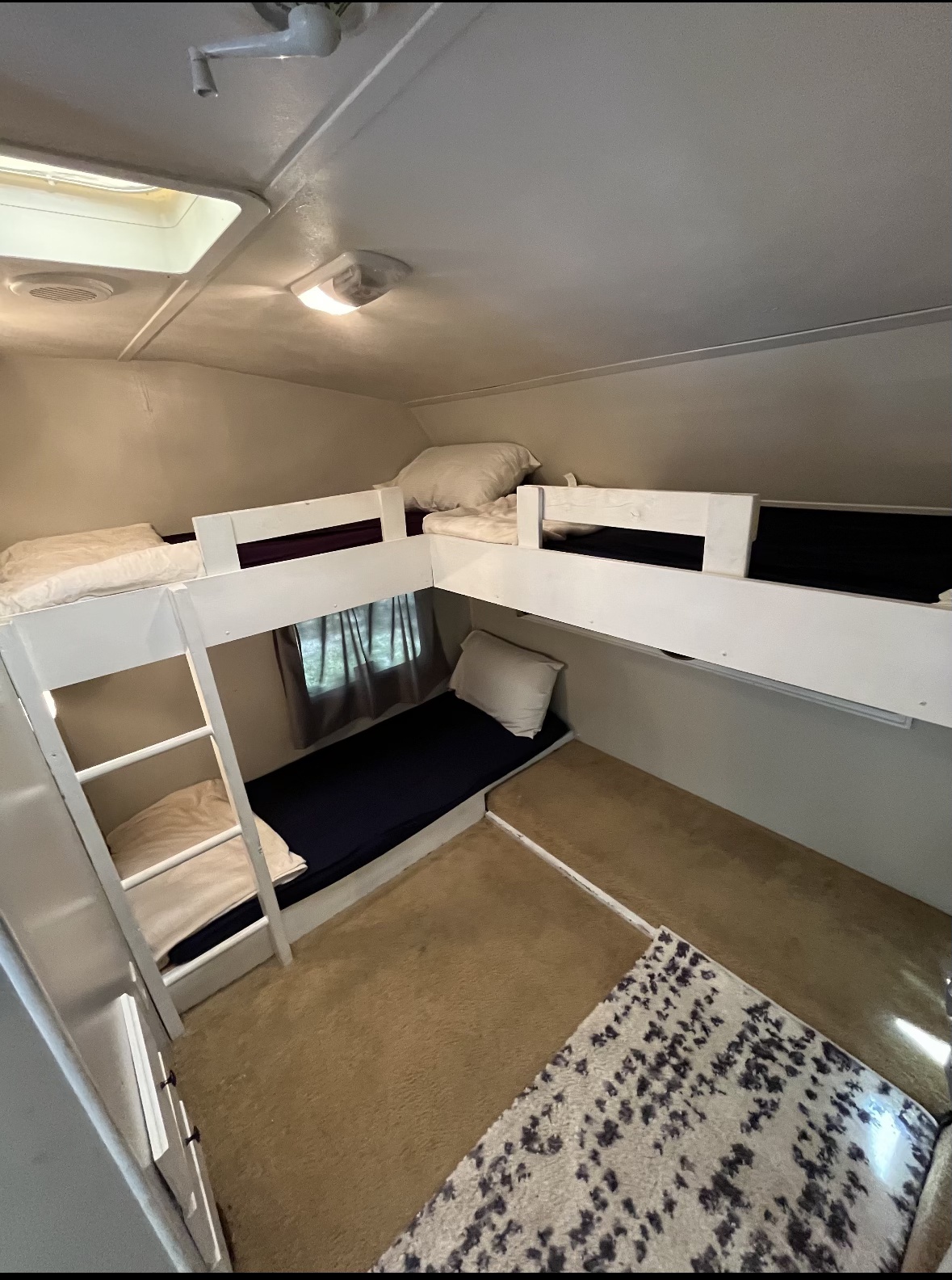 RV rental interior showcasing multiple white bunk beds with bedding and a ladder, maximizing sleeping space on a carpeted floor.. Forest River Wildcat 2011