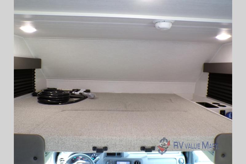 Cozy over-cab sleeping area in this RV rental. Features a comfortable bunk, interior lights, and smoke detector for safety.. East to West Entrada 2026