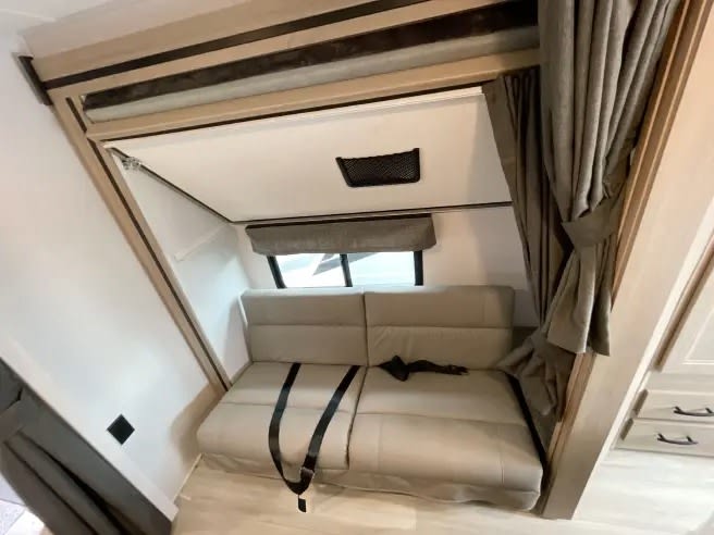 RV rental interior: a versatile convertible sofa with seat belts below a fold-down bunk bed, offering compact sleeping.. Forest River Forester 2026