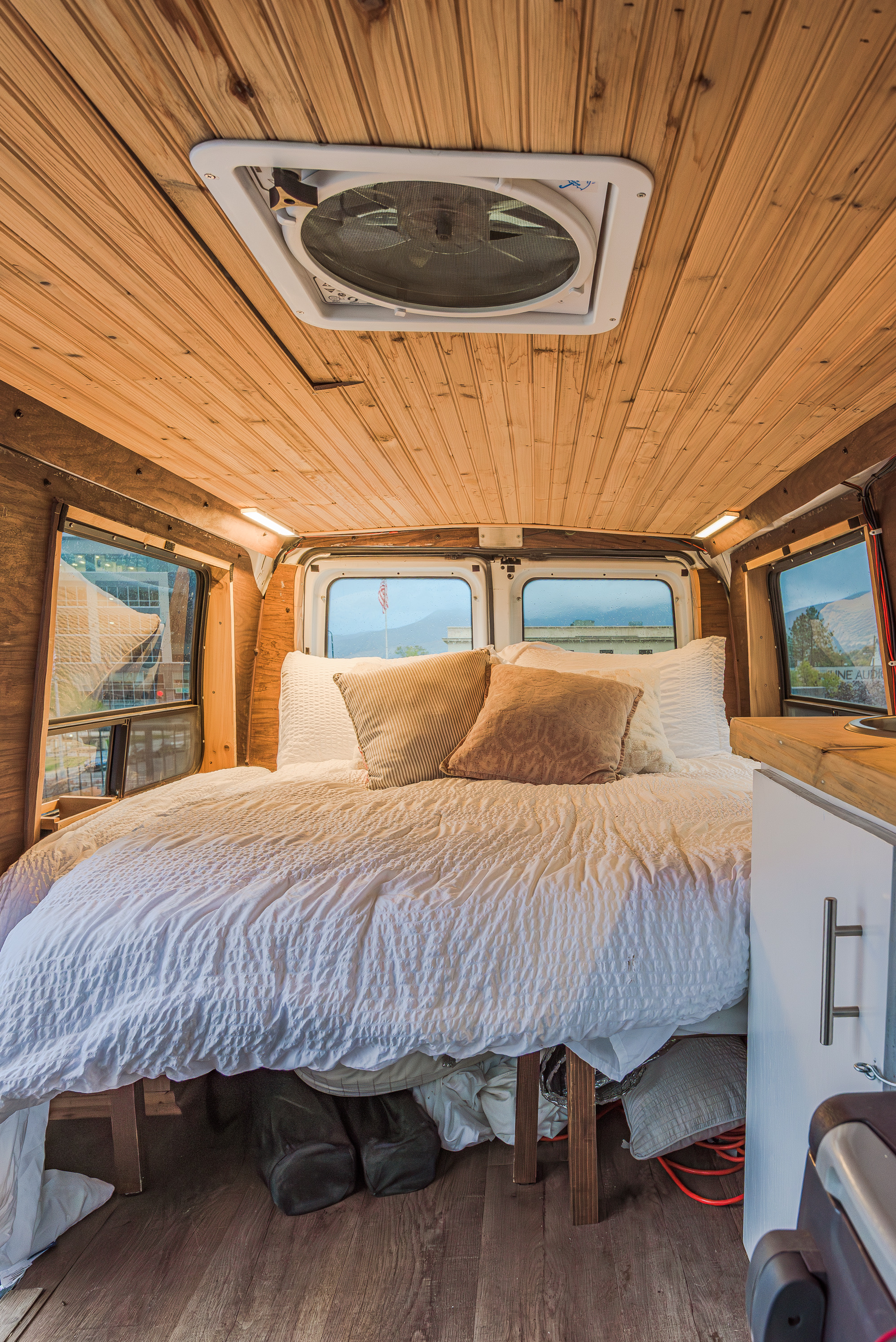 Cozy RV rental interior featuring a comfortable bed, wooden paneling, roof fan, and window views.. Ford Econoline E250supercab 2008