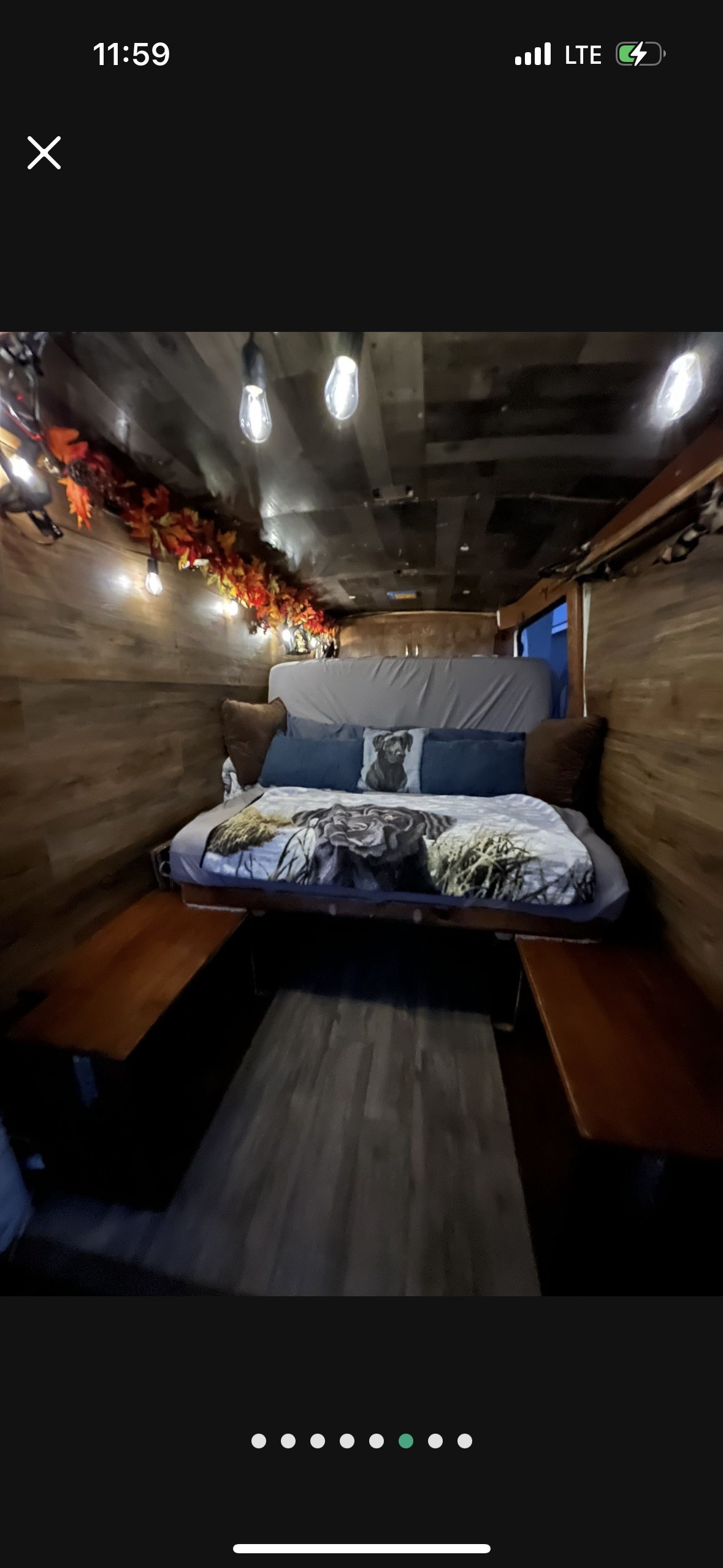 Cozy rv rental interior: wood-paneled bedroom features dog-themed bedding, string lights, and autumn leaf decor.. Nissan PRIMASTAR 2013