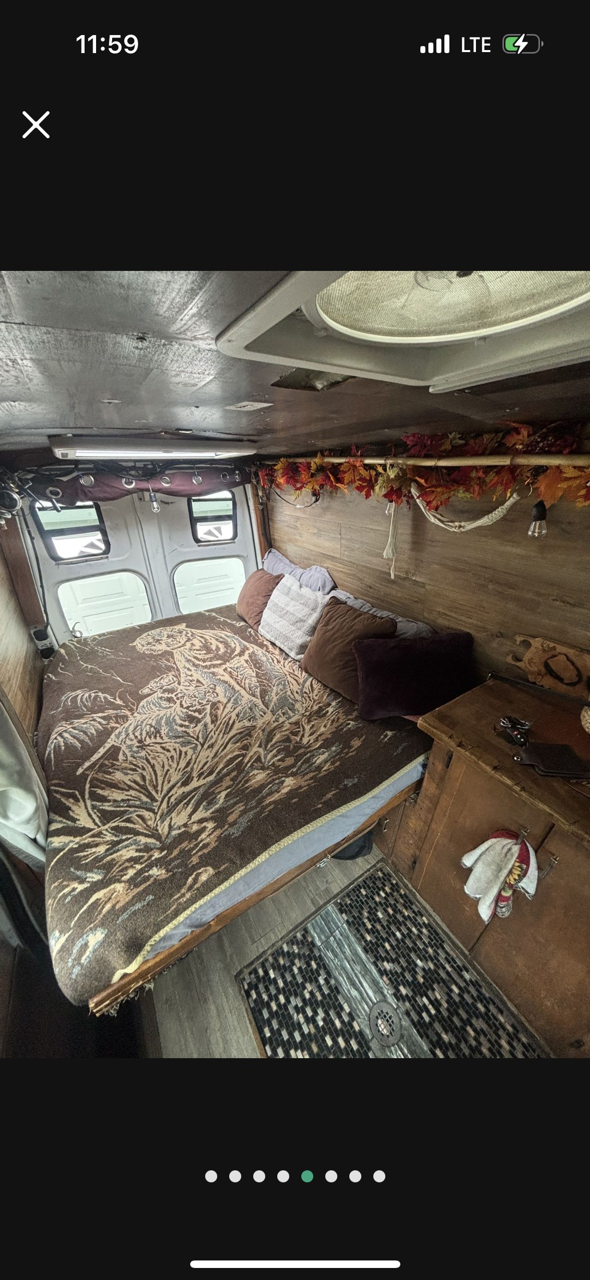 Inside this rv rental: A comfy bed with a tiger blanket, rustic wood paneling, ceiling fan, and charming fall decorations.. Nissan PRIMASTAR 2013