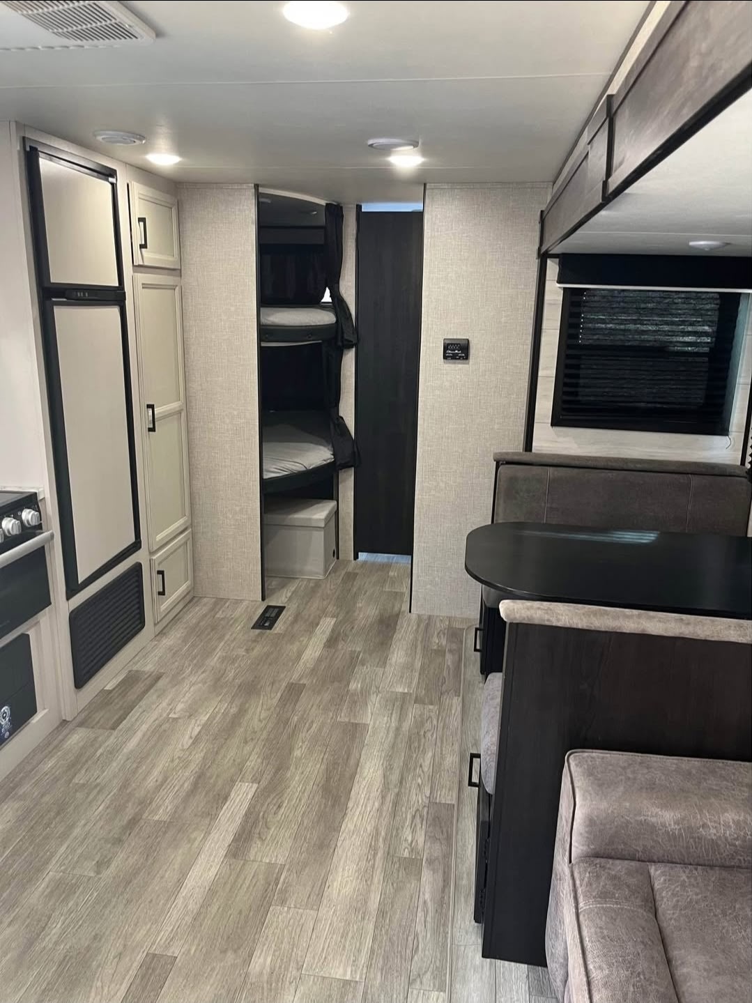 Spacious rv rental interior showing bunk beds, a kitchen with fridge & stove, and a dinette. Ideal for family road trips.. Jayco Jay Flight Baja Edition 2023