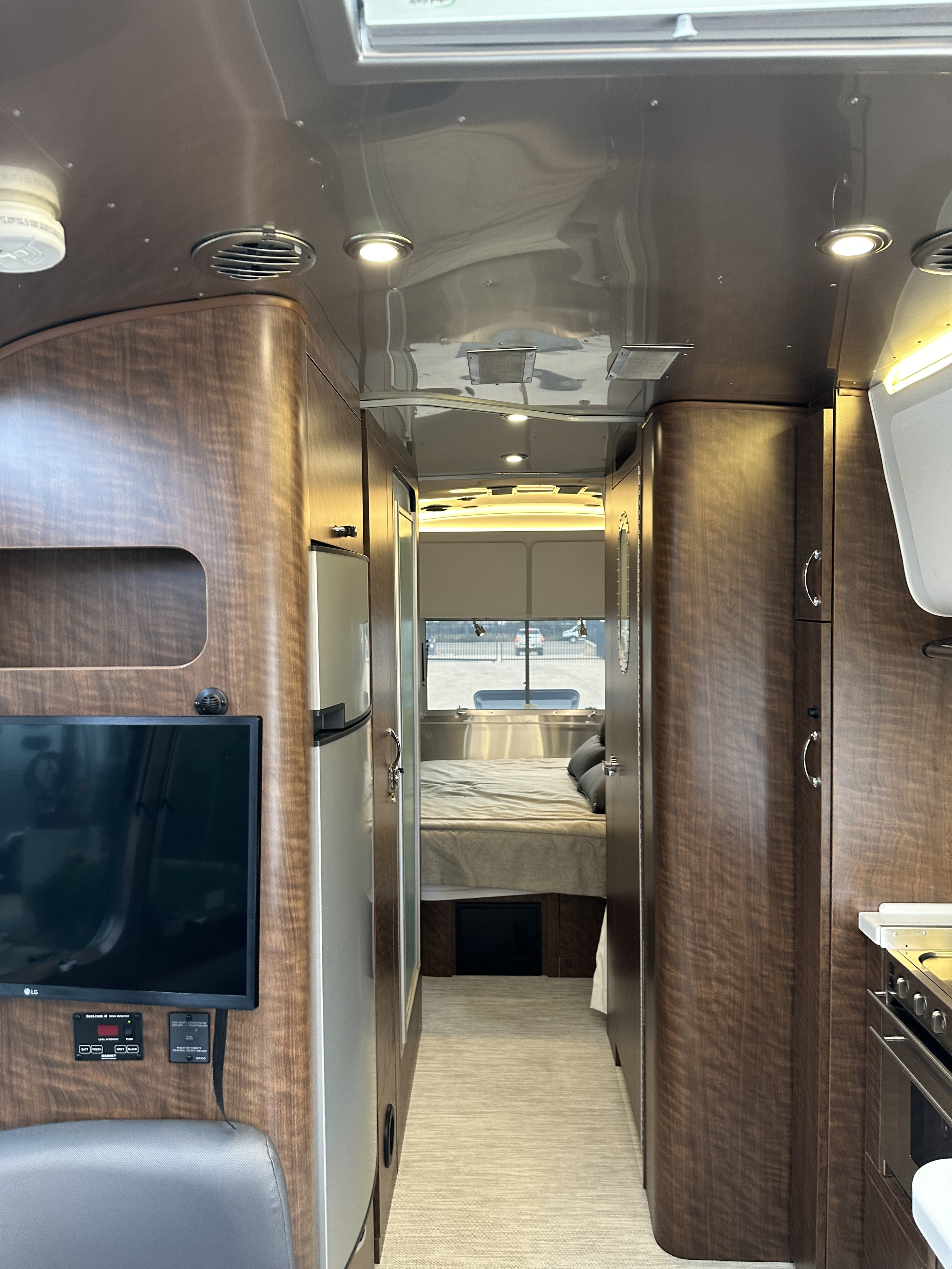 Experience comfort in this stylish rv rental. View of a modern camper interior with wood-grain cabinets, cozy bed, and living area.. Airstream Globetrotter 2020