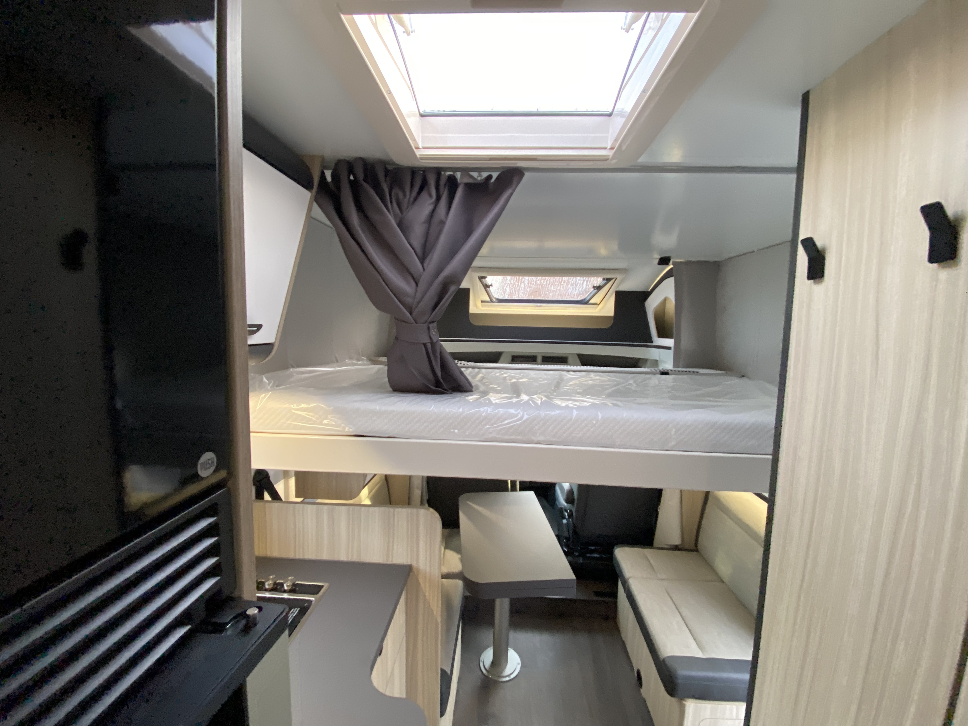 RV rental interior: an elevated bed, compact kitchen, dining area with seating, and skylight, designed for comfort.. Sun living Serie S 72 DL 2026