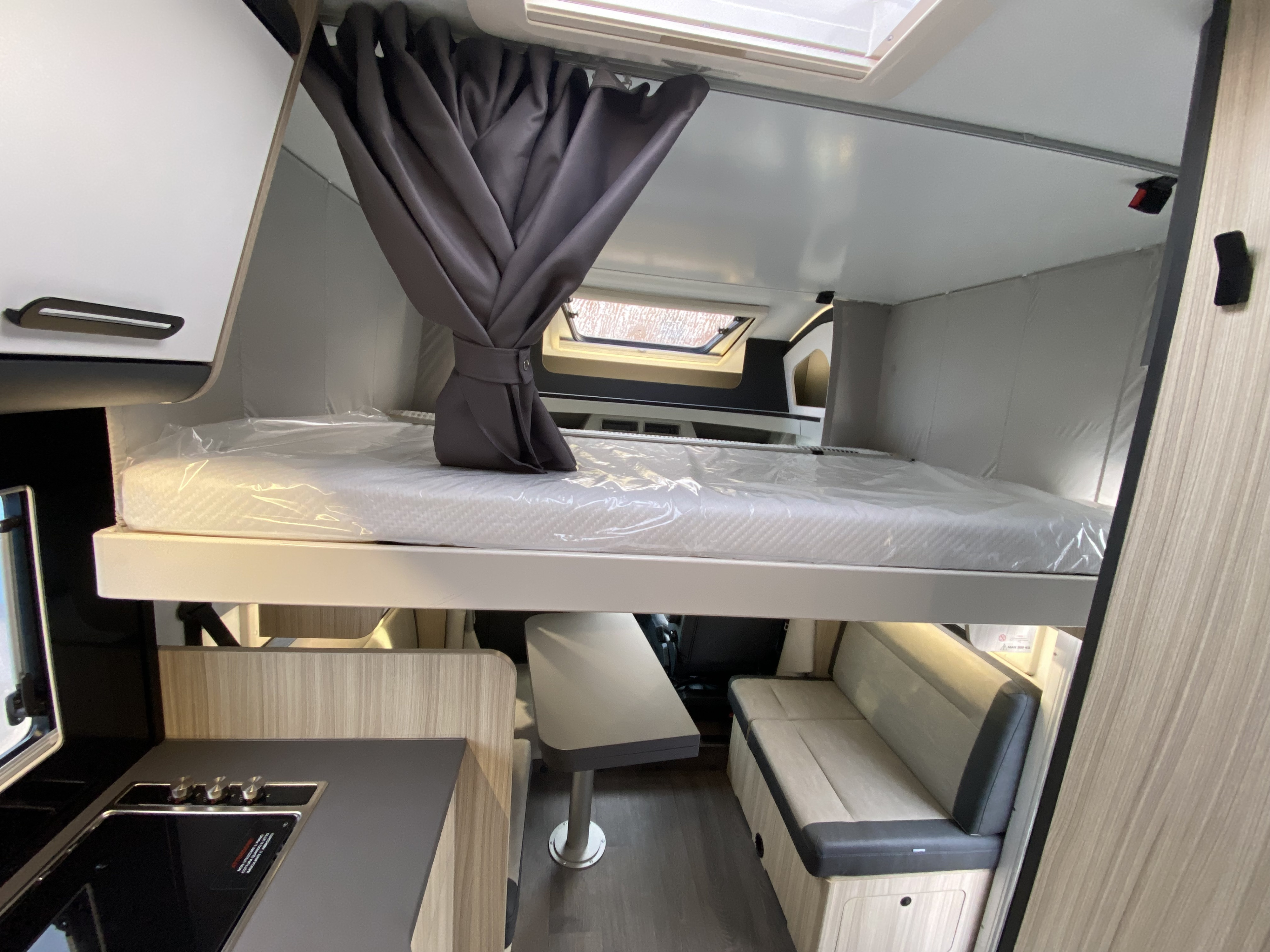 Bright rv rental interior: drop-down bunk bed above kitchen, dining table, and bench seating. Functional & stylish.. Sun living Serie S 72 DL 2026