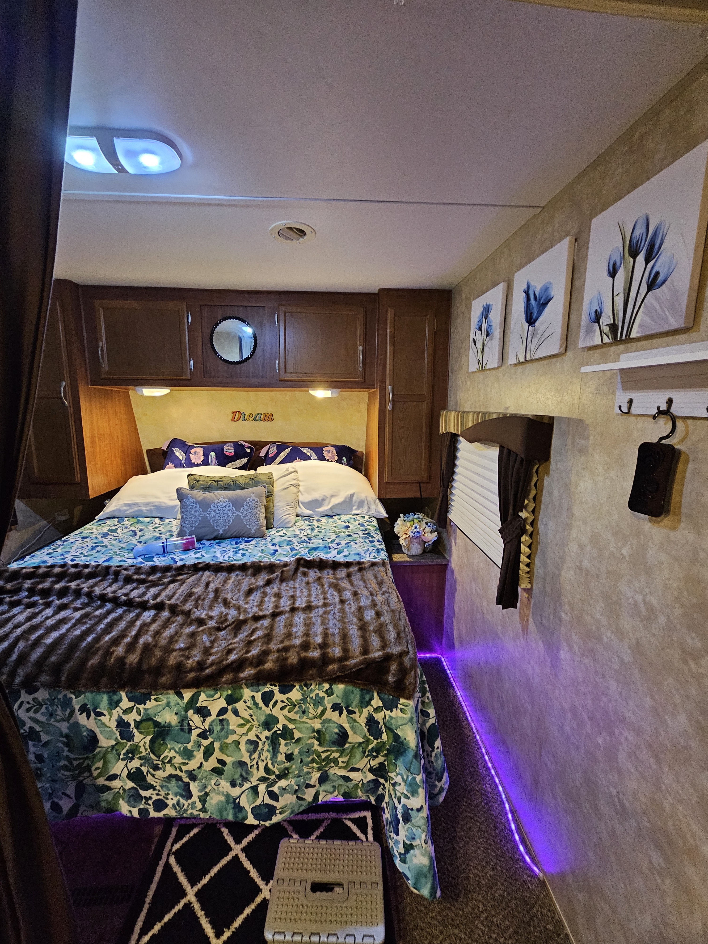 Cozy RV rental bedroom with floral bedding, a "Dream" sign, and ambient purple lighting for a comfortable camper stay.. Jayco Jay Flight 2010