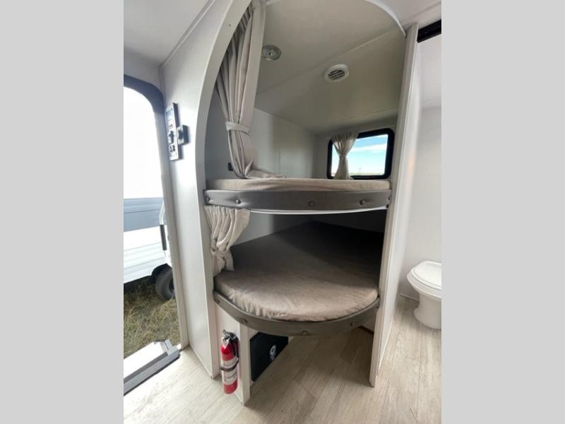 This compact rv rental interior features two curved bunk beds with privacy curtains, a window, and a compact toilet.. Forest River Salem Cruise Lite 26ICE 2025