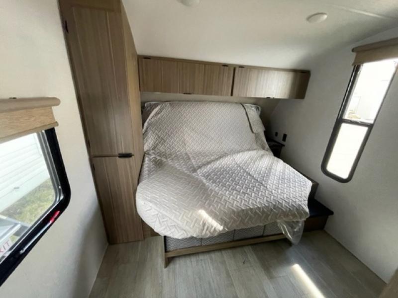 Clean RV rental bedroom with a covered bed, wood cabinets, a wardrobe, and windows for natural light.. Forest River Salem Cruise Lite 26ICE 2025