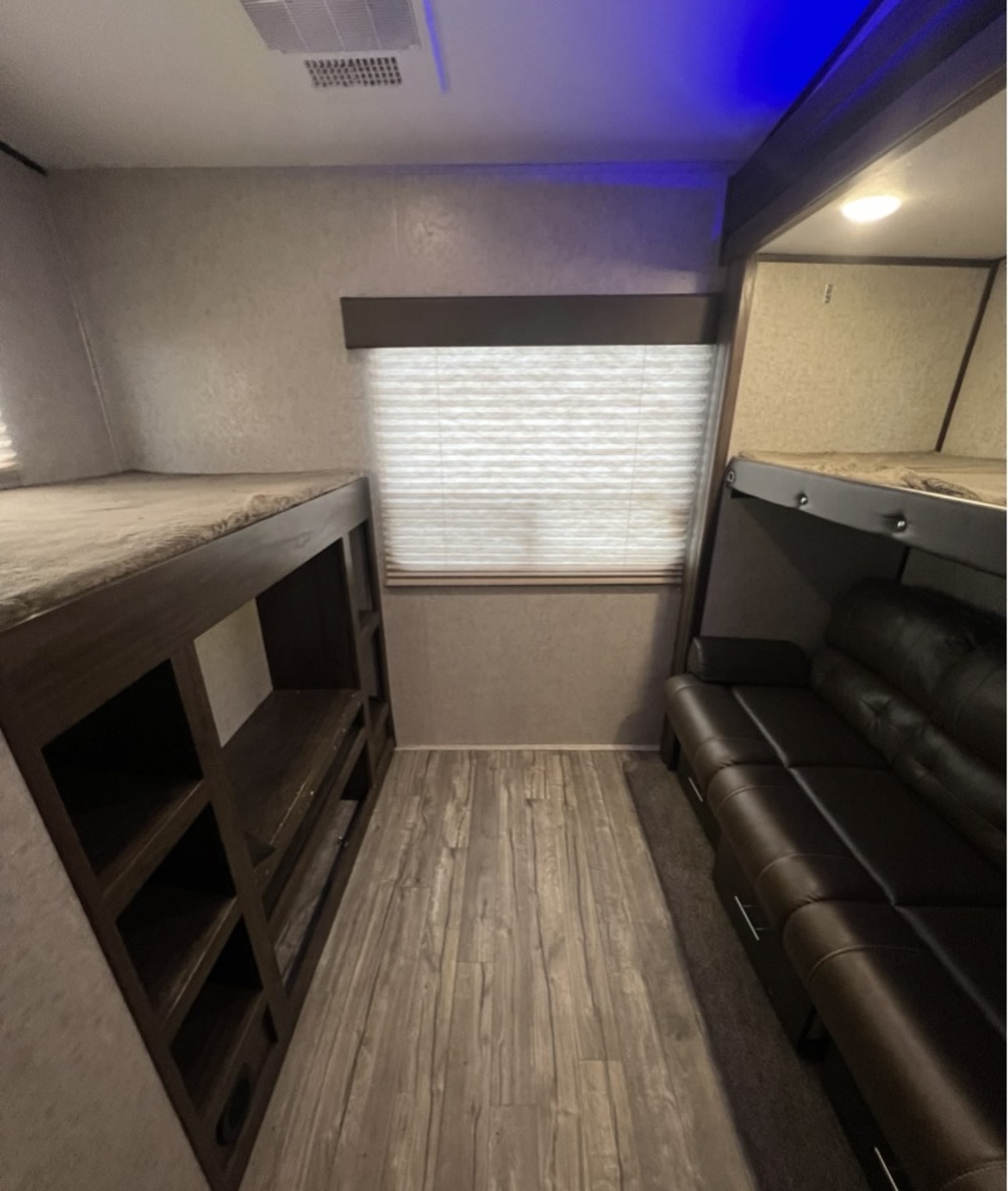RV rental interior: Bunk beds, sofa, and a window are visible in this compact RV sleeping and living space.. Forest River Cherokee Arctic Wolf 2018