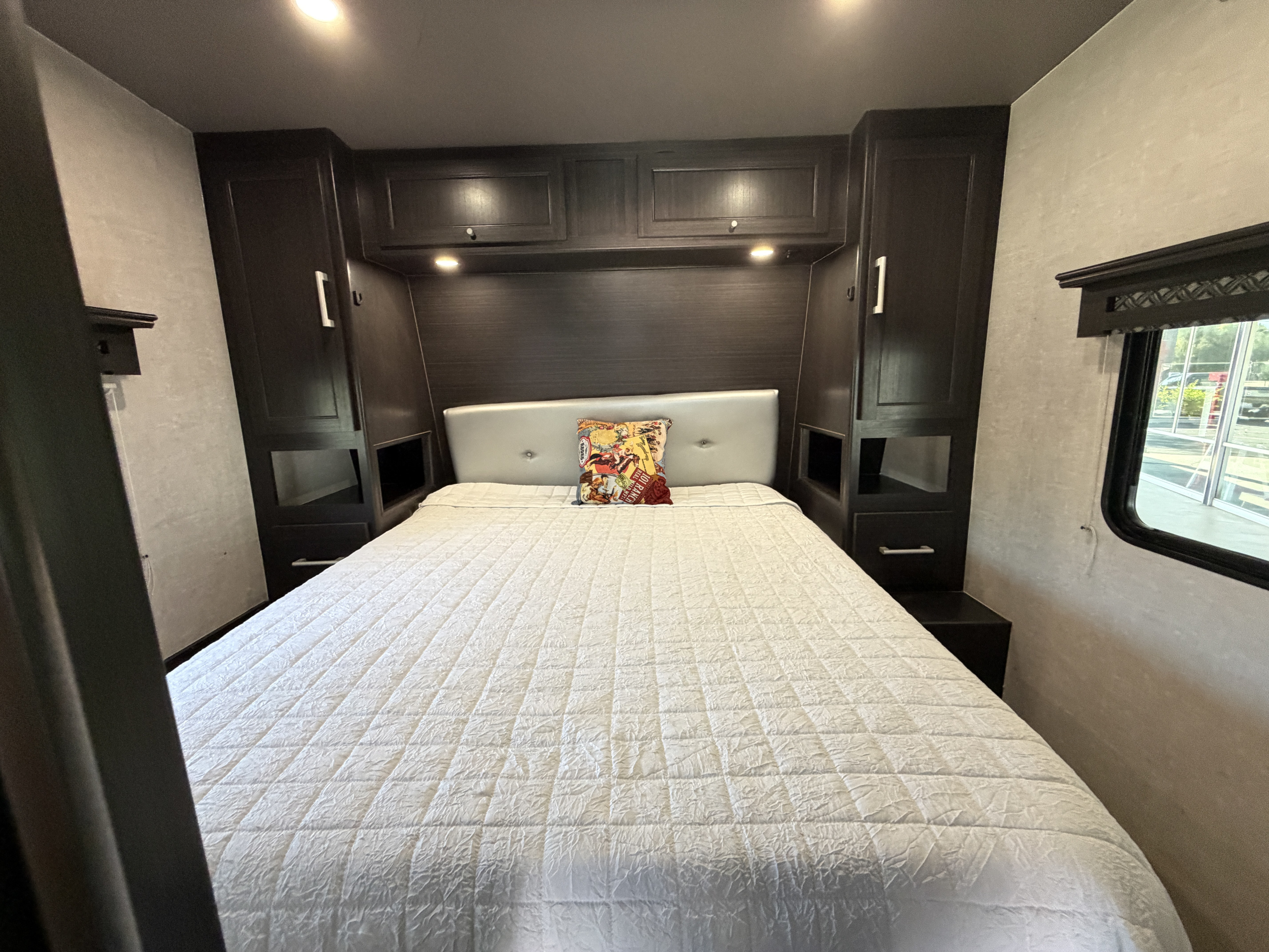Comfortable RV rental bedroom with dark wood cabinetry, a padded headboard, and a cozy white bed, perfect for your next adventure.. Eclipse Stellar Pro Lite Toy Hauler 2020