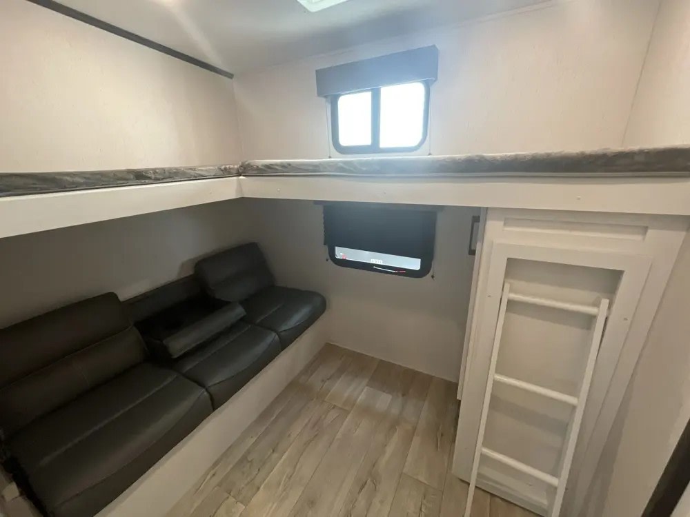 This RV rental features a cozy interior with bunk beds, a convertible sofa, and a window, ideal for extra sleeping and lounging space.. Dutchmen Other 2024