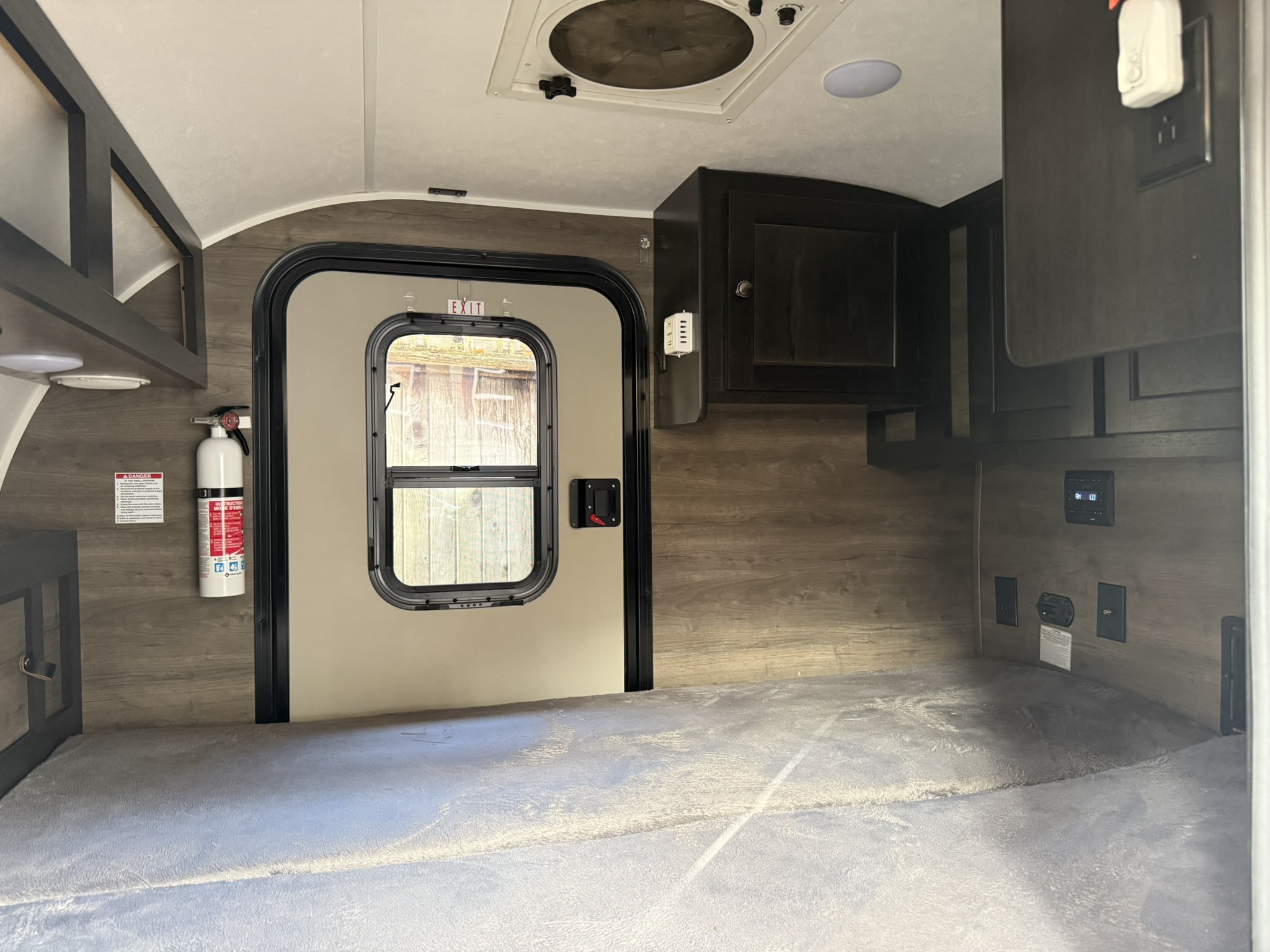 Inside a cozy rv rental: a bed, door, fire extinguisher, and overhead cabinets, ready for your next travel adventure.. Braxton Creek Bushwhacker 2022