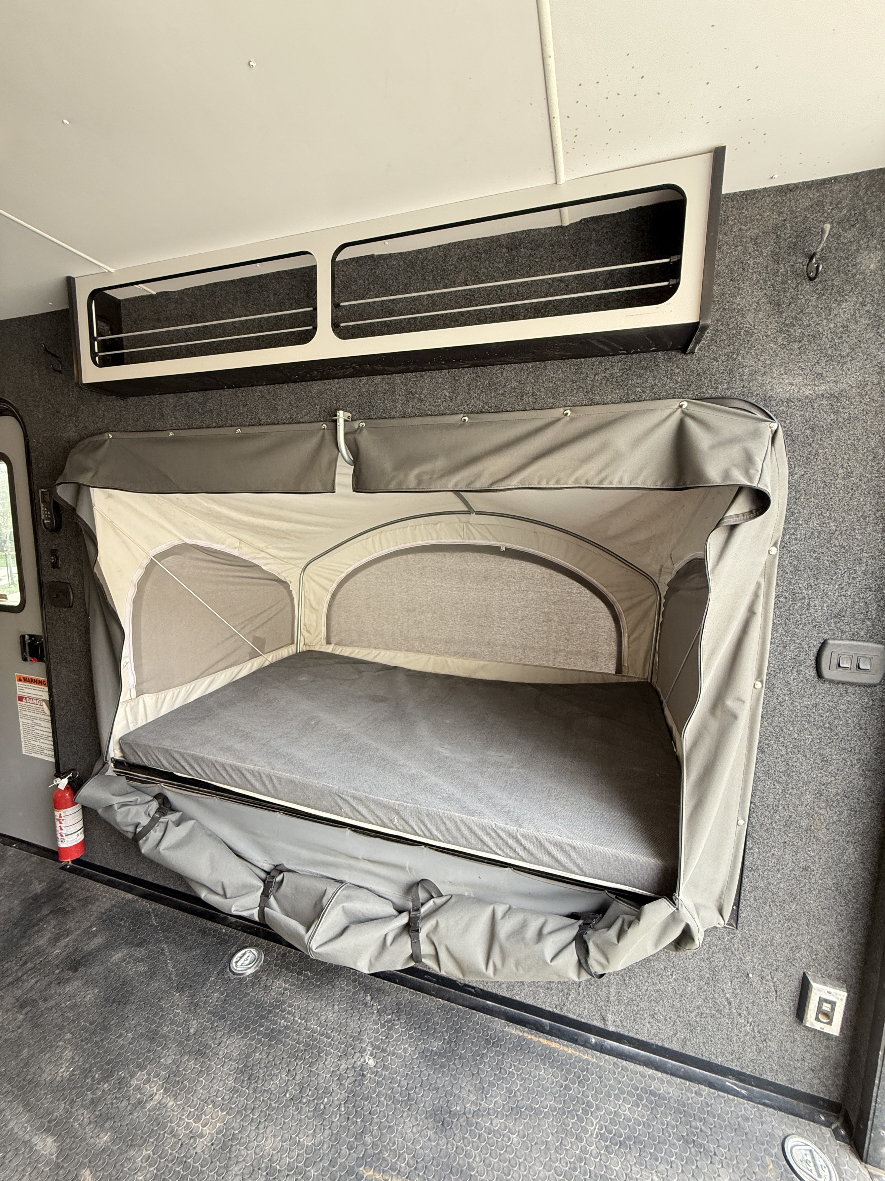 RV rental: Interior shot showing a pull-down bunk bed with mattress, overhead storage, and a rugged utility space.. InTech RV InTech RV Trailer 2022