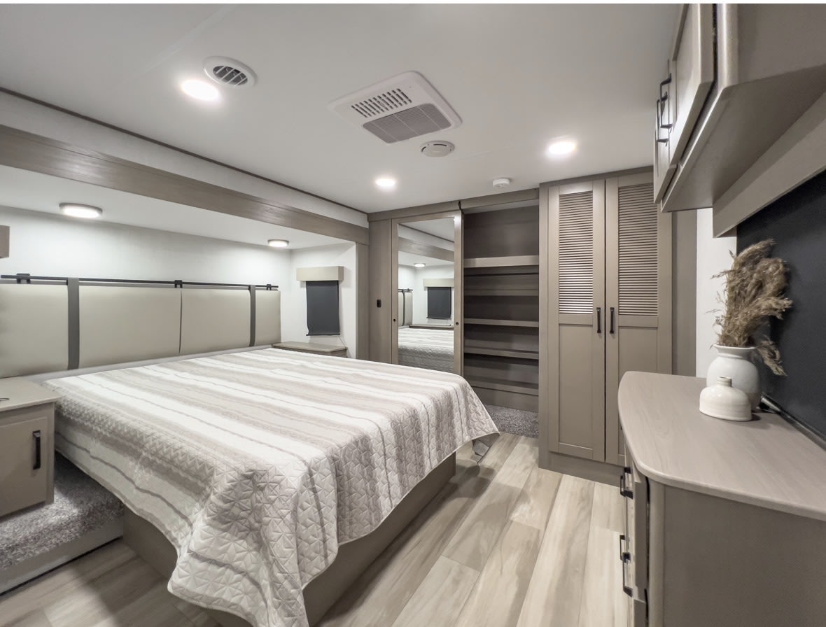 Spacious and modern RV rental bedroom featuring a large bed, ample storage, and sleek design. Perfect for travel comfort.. Grand Design Reflection 2025