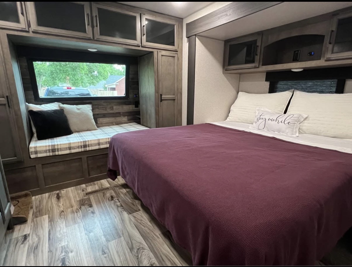 Explore this inviting RV rental interior: a comfy bed, cozy window seat, and storage. Ideal for your next journey.. Venture SportTrek Touring 2022