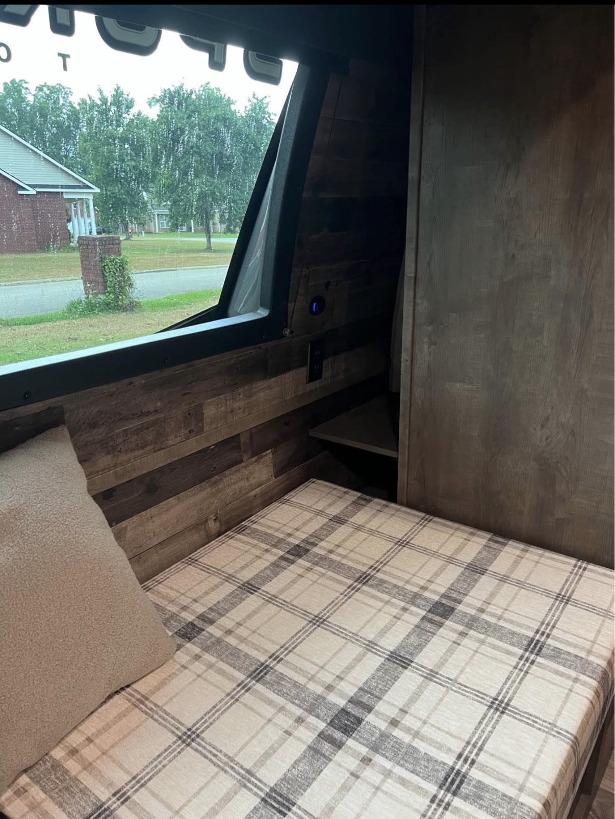 Inside a cozy rv rental: Plaid bed, wood walls, and a window with a green view. Perfect for relaxation.. Venture SportTrek Touring 2022
