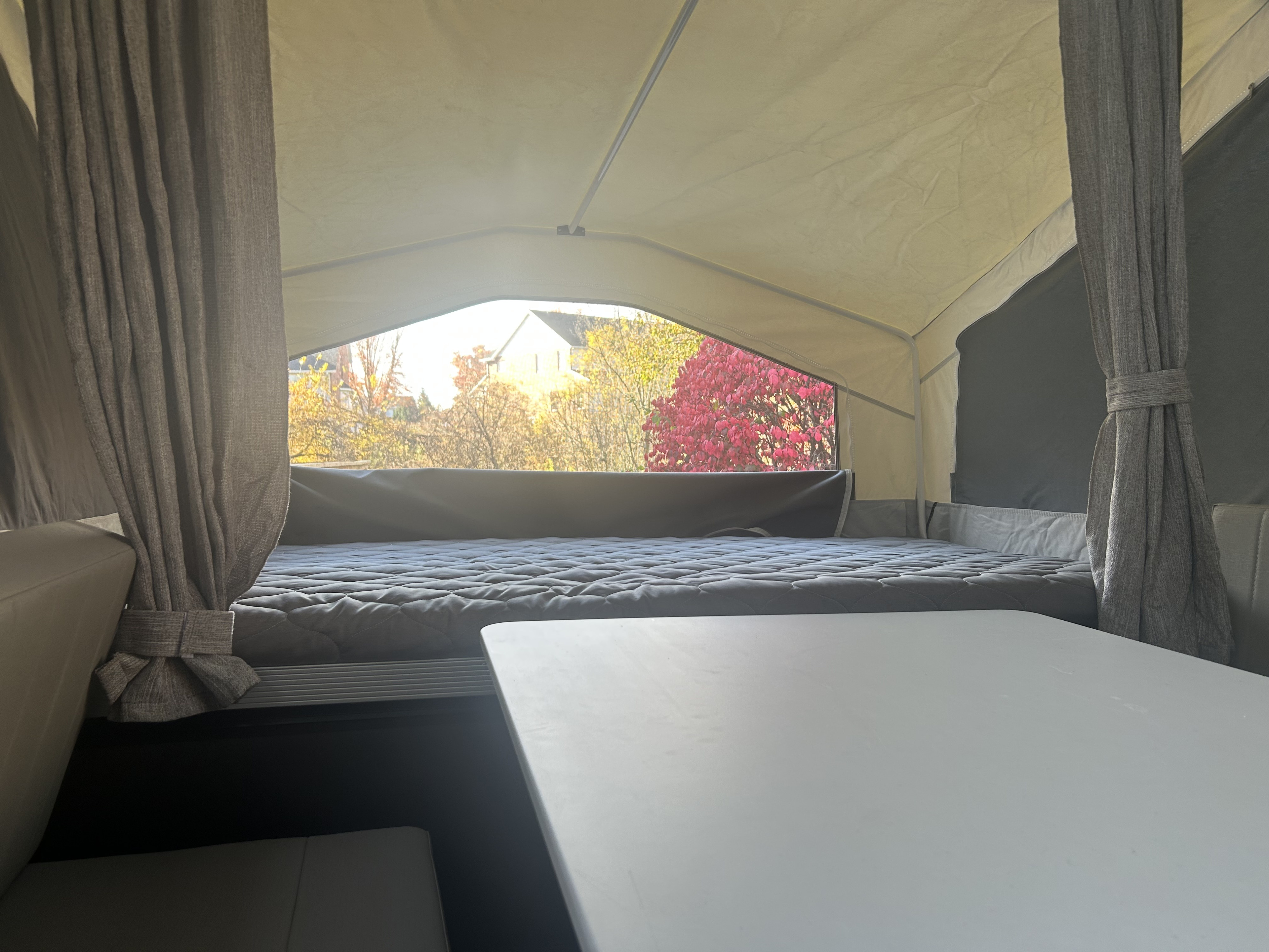 Cozy pop-up camper interior from an RV rental, featuring a bed, table, and scenic autumn view for your travel adventure.. Forest River Flagstaff 2026