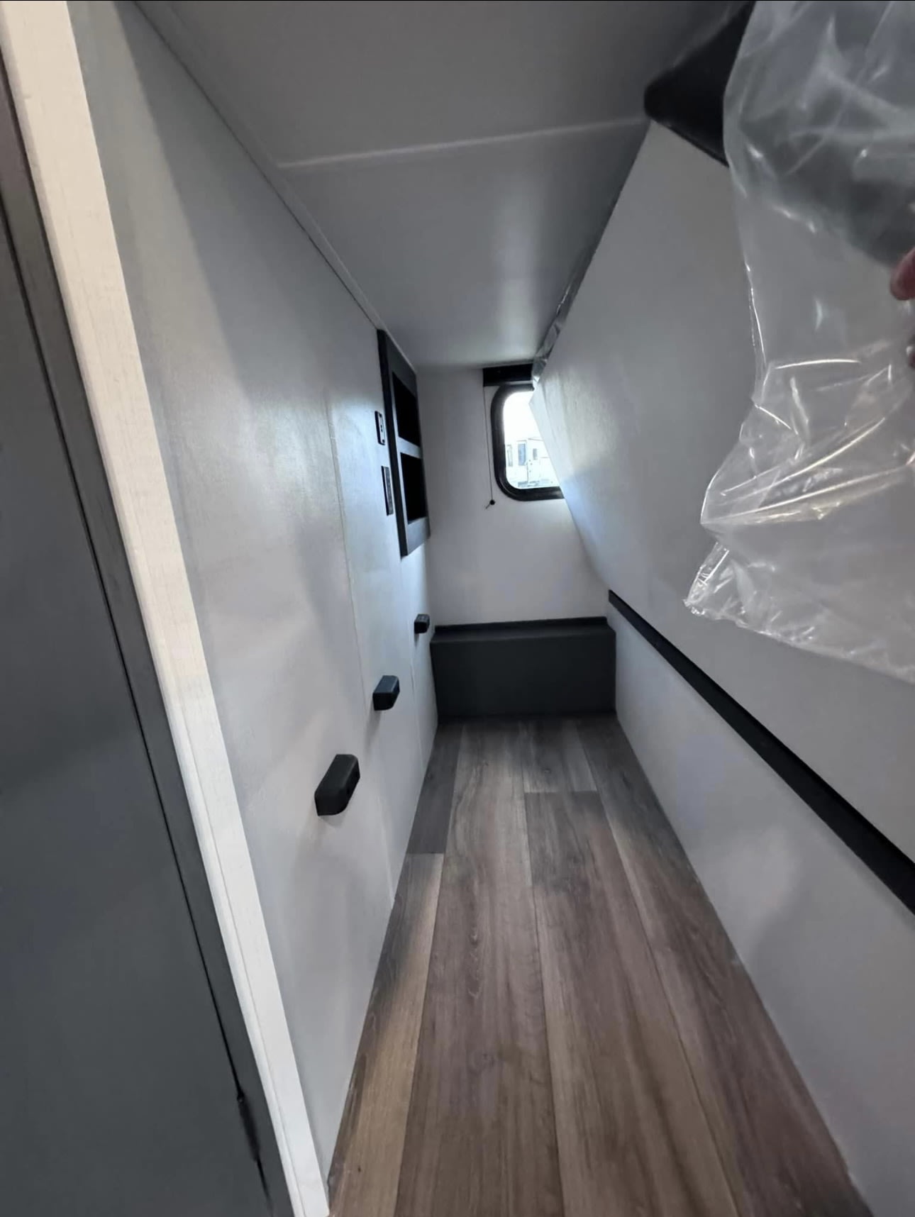 Inside an RV rental: a lifted bed reveals spacious under-bed storage. Features wood-look floor, window, and wall hooks.. Keystone RV Bullet Ultra Lite 2024