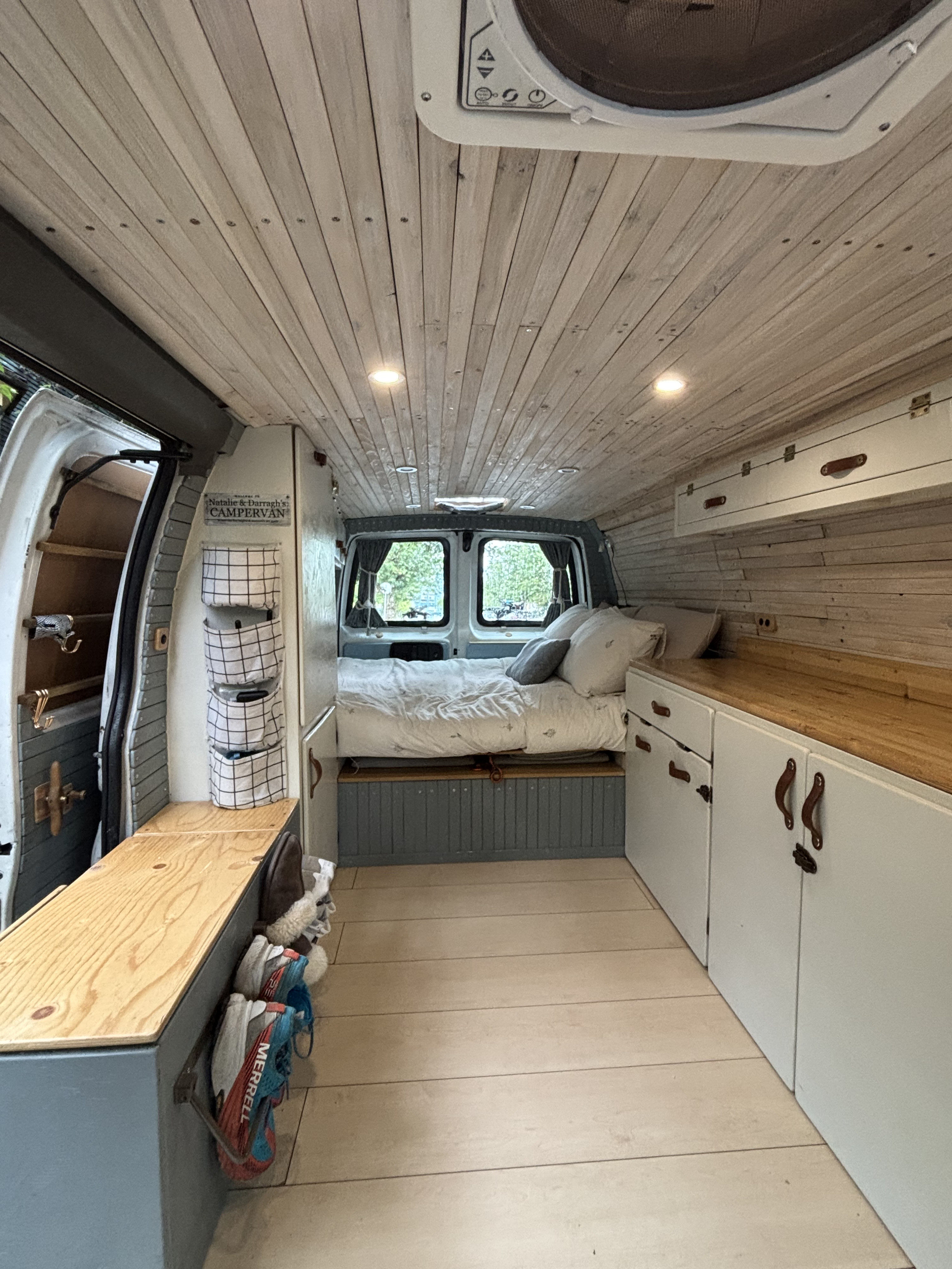 Detailed view of a customized campervan interior featuring a bed, storage, wood paneling, and compact living, ideal for RV rental.. Chevrolet Express 2005