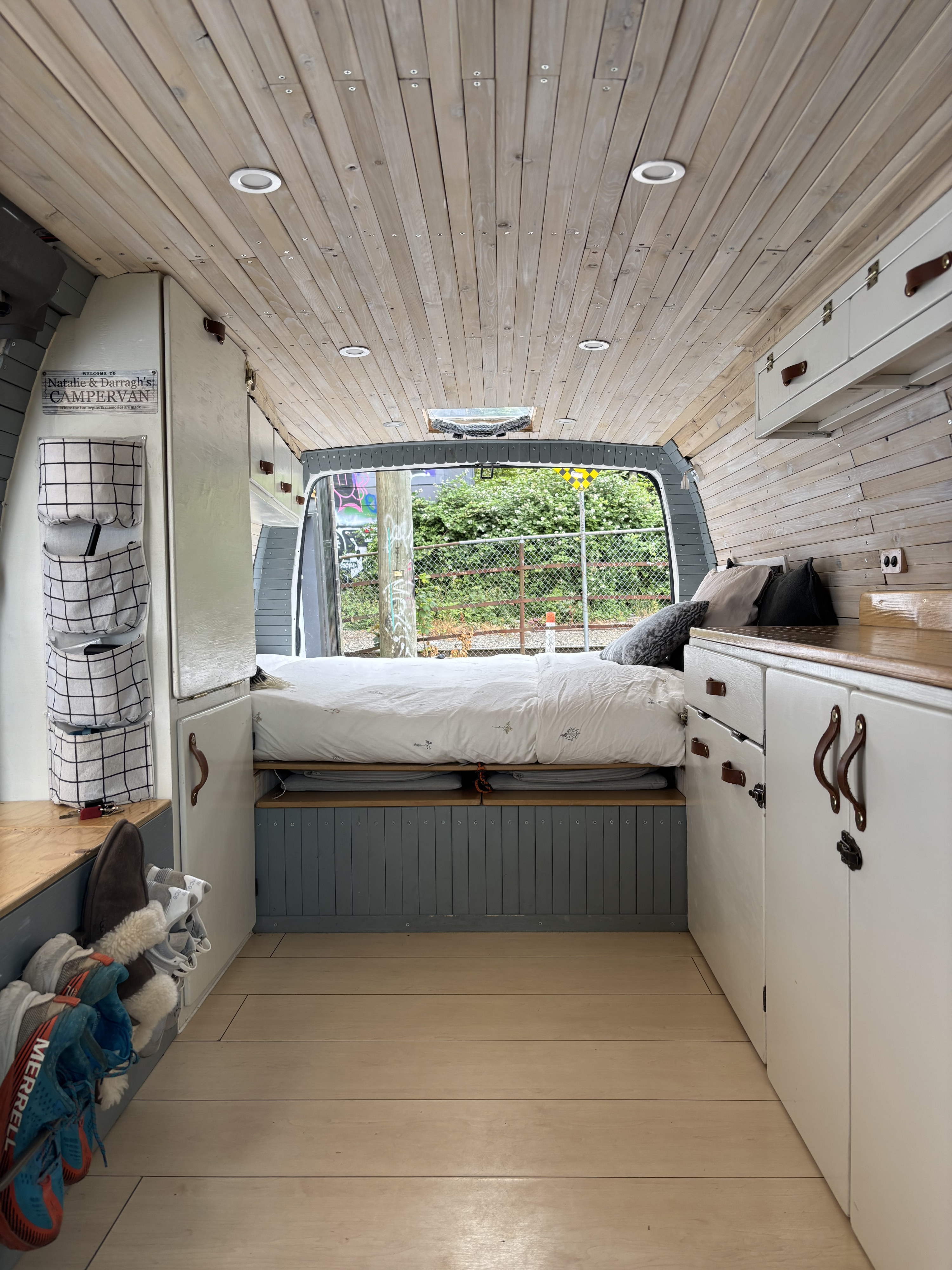 RV rental campervan interior: light wood, comfy bed, recessed lighting, smart storage, and an open back with outdoor view.. Chevrolet Express 2005