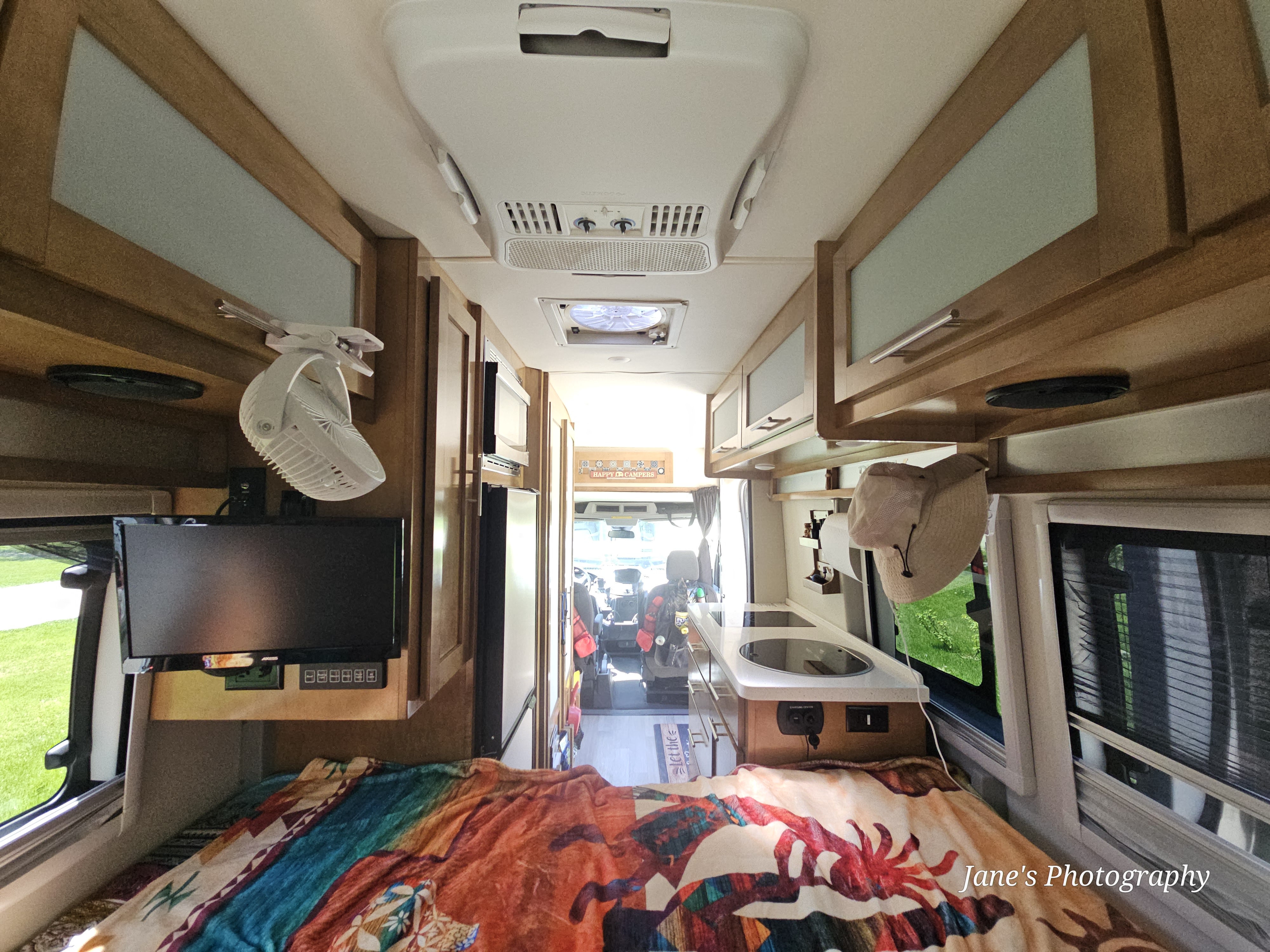 Interior of an RV rental, looking forward from the bed to the kitchenette, overhead cabinets, and driver's cockpit.. Forest River Coachmen Crossfit 2019
