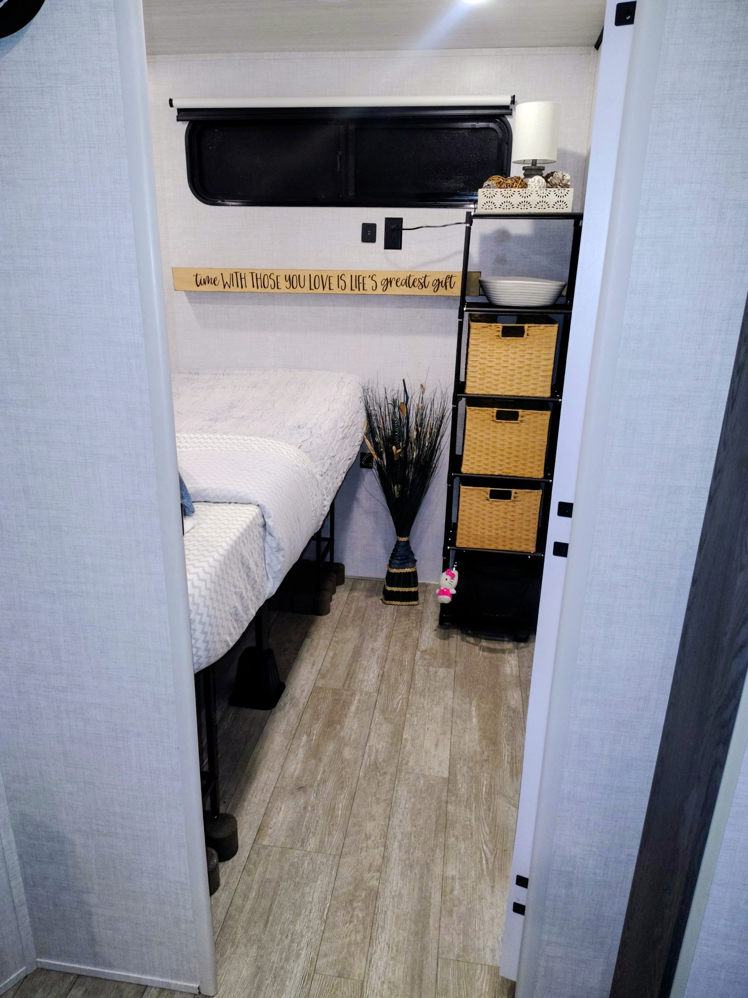 Cozy RV rental bedroom with a neatly made bed, storage shelves, and decorative accents, viewed from the doorway.. Forest River Impression 2023