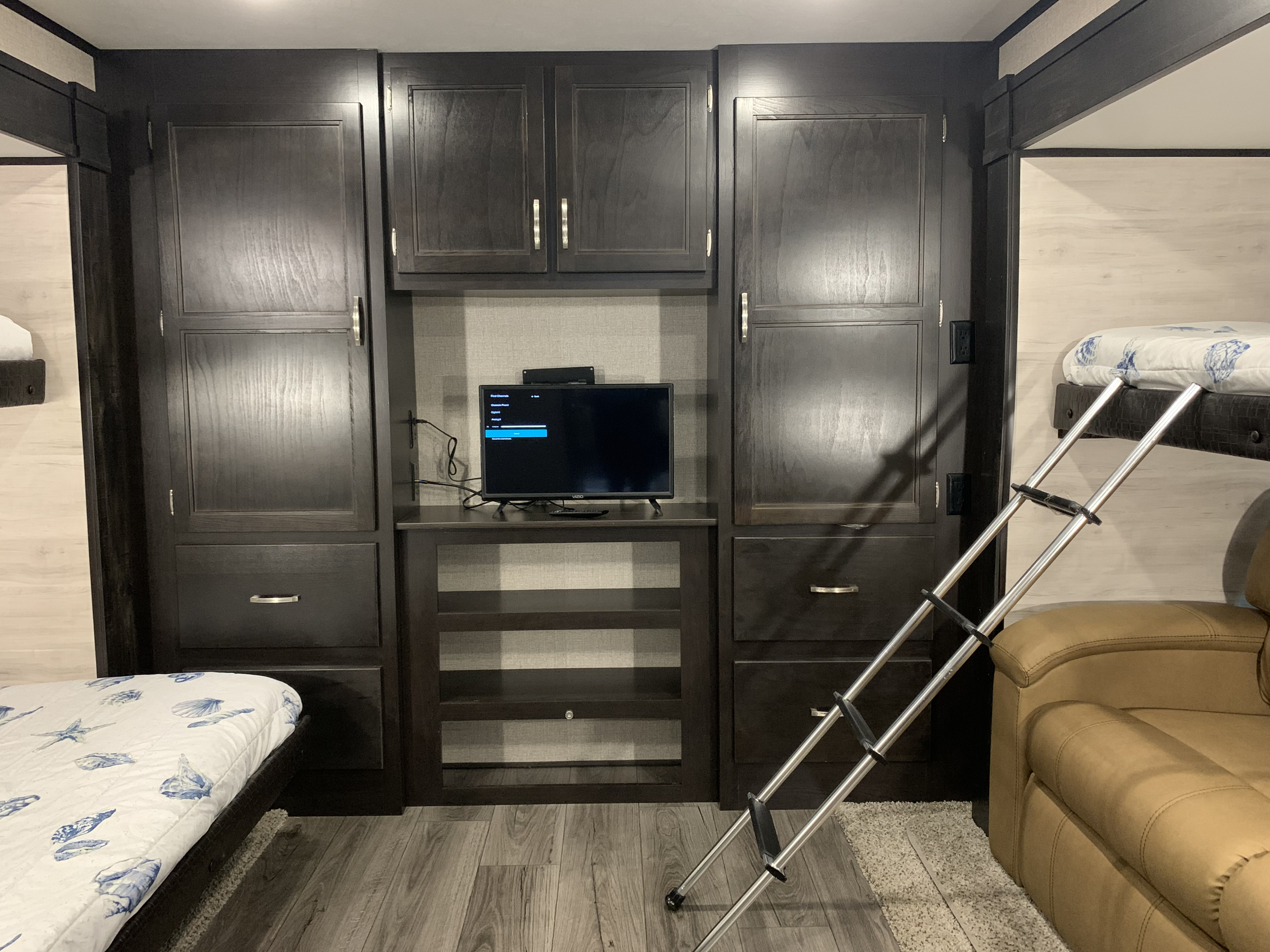 Cozy rv rental interior featuring bunk beds, a TV, and ample dark wood storage for a comfortable stay.. Jayco Jay Flight 2021