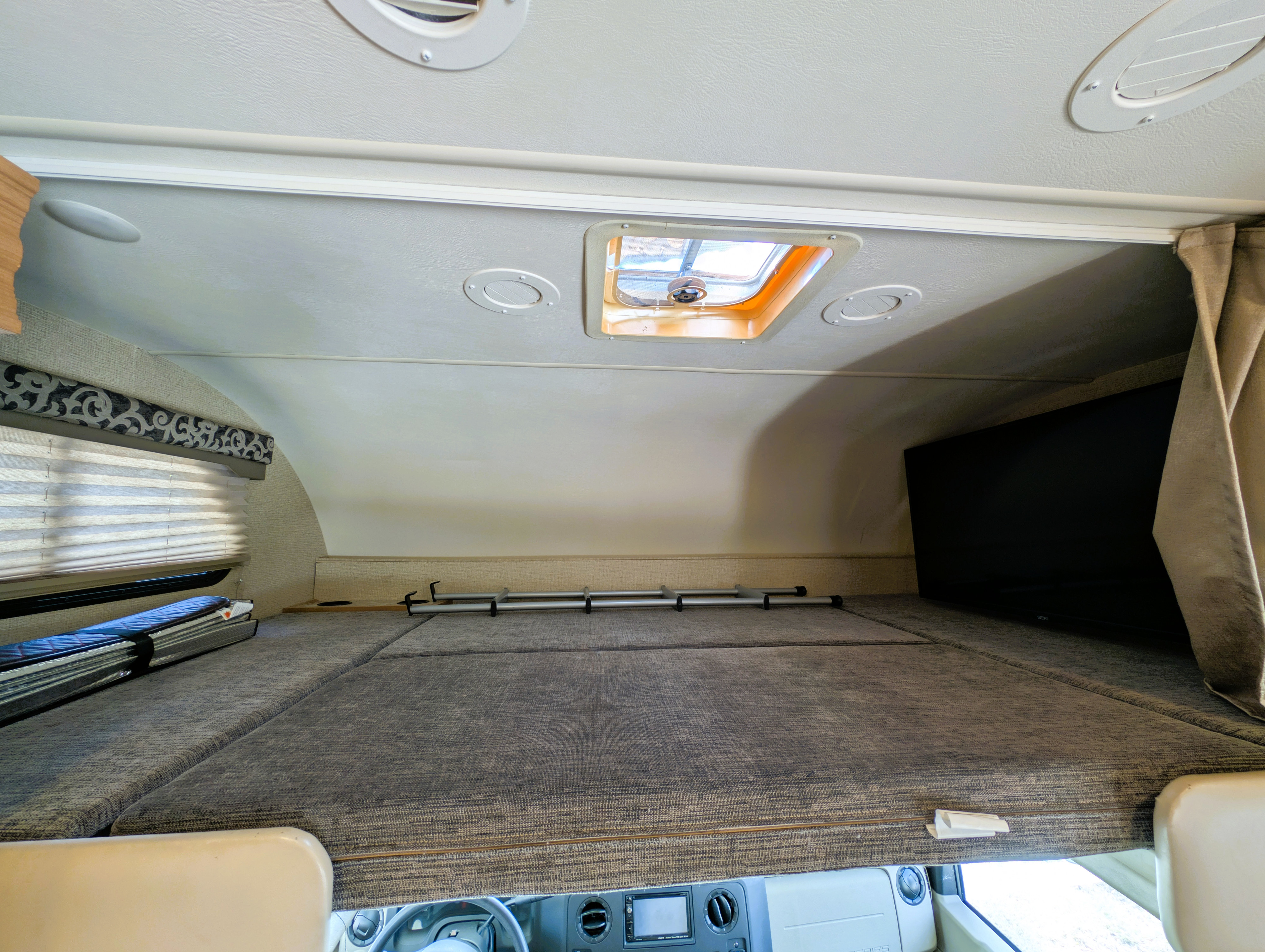 Cozy overhead bunk bed in this RV rental, featuring a skylight, TV, and blinds. Ideal for family travel!. Thor Four Winds 2017