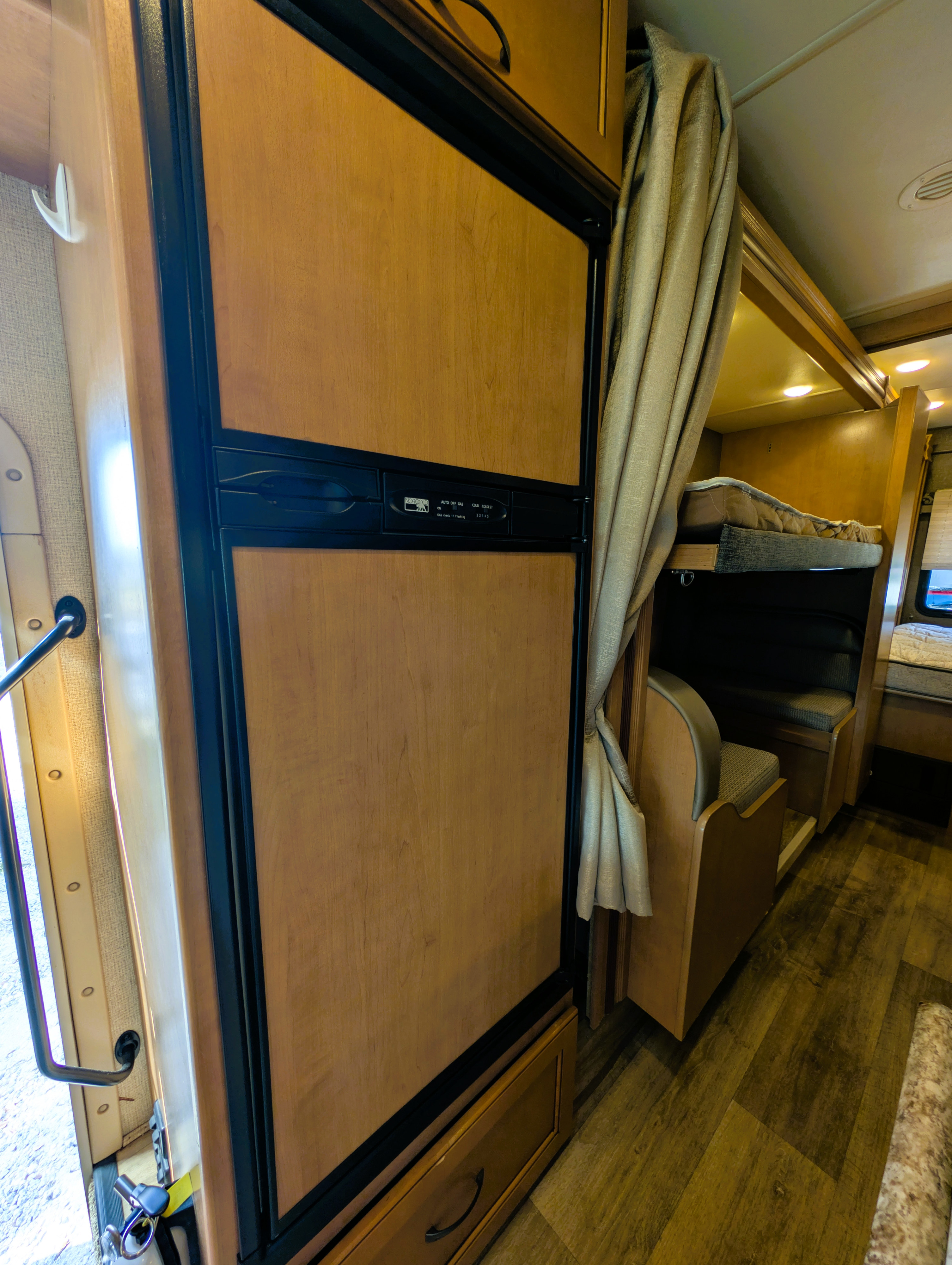 RV rental: Cozy interior featuring a wood-paneled fridge, bunk beds with privacy curtain, and dinette. Perfect for road trips.. Thor Four Winds 2017