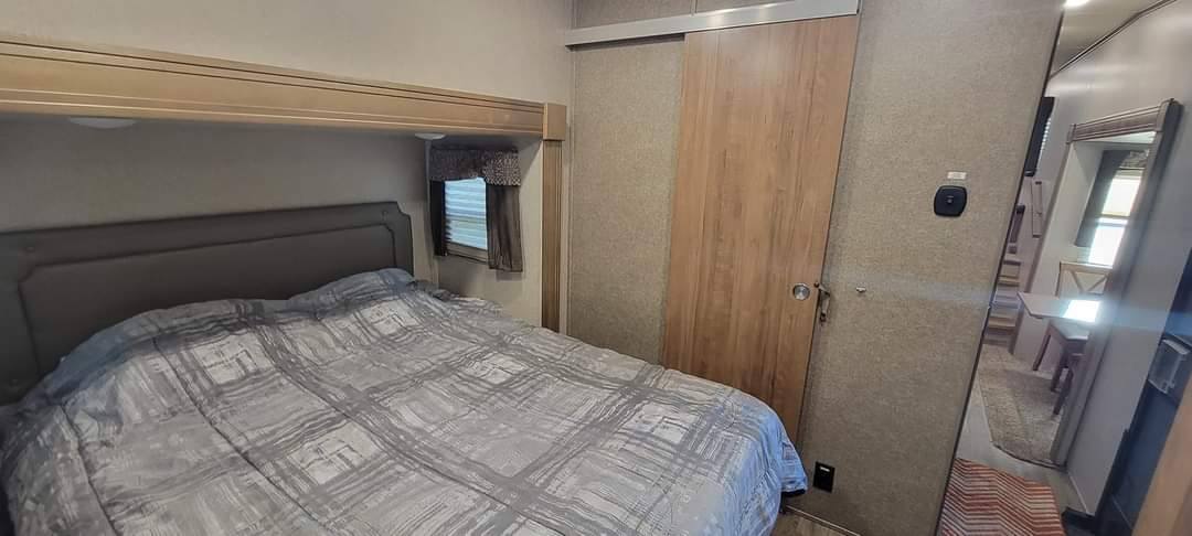 RV rental bedroom featuring a comfy bed, window, sliding door, and mirrored view of the interior.. Forest River Flagstaff Super Lite 2018