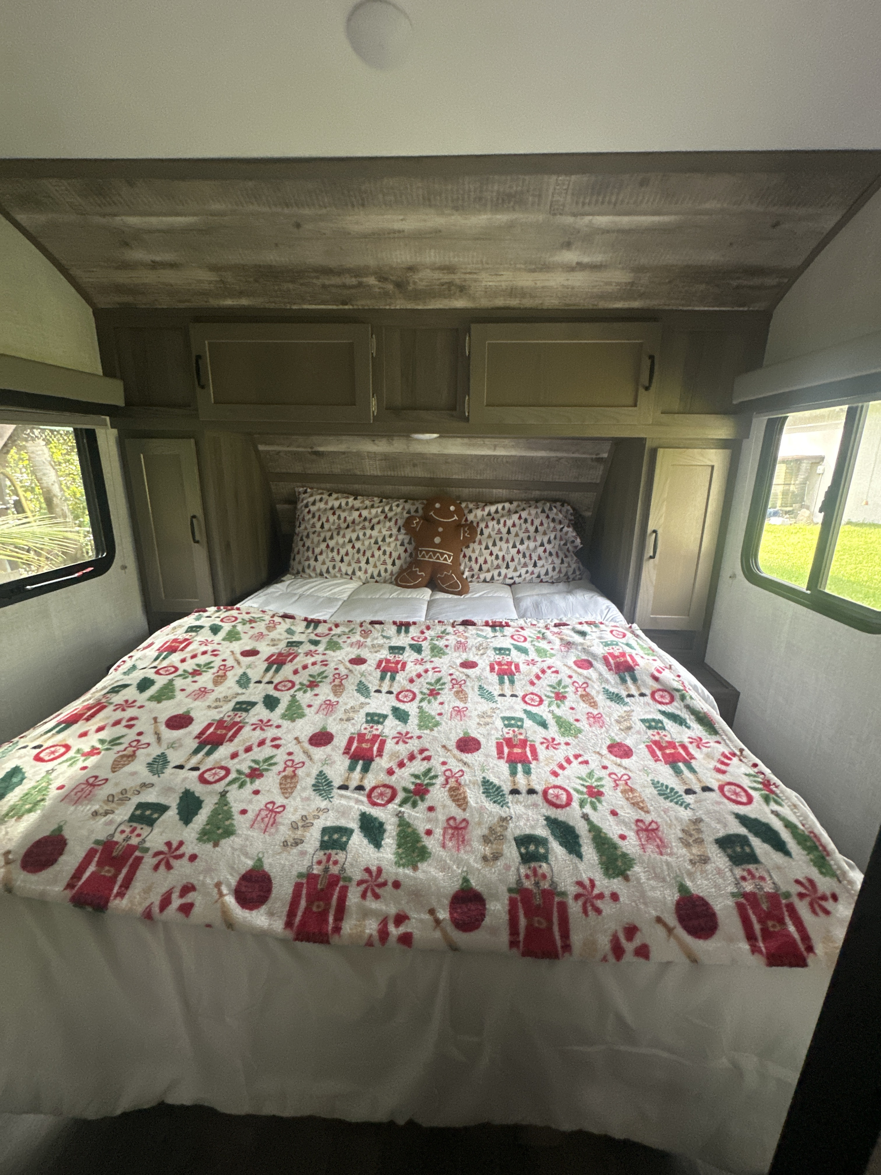 Cozy RV rental bedroom with a holiday nutcracker blanket, white comforter, and a gingerbread man plush on the bed.. Gulf Stream Vista Cruiser 2022