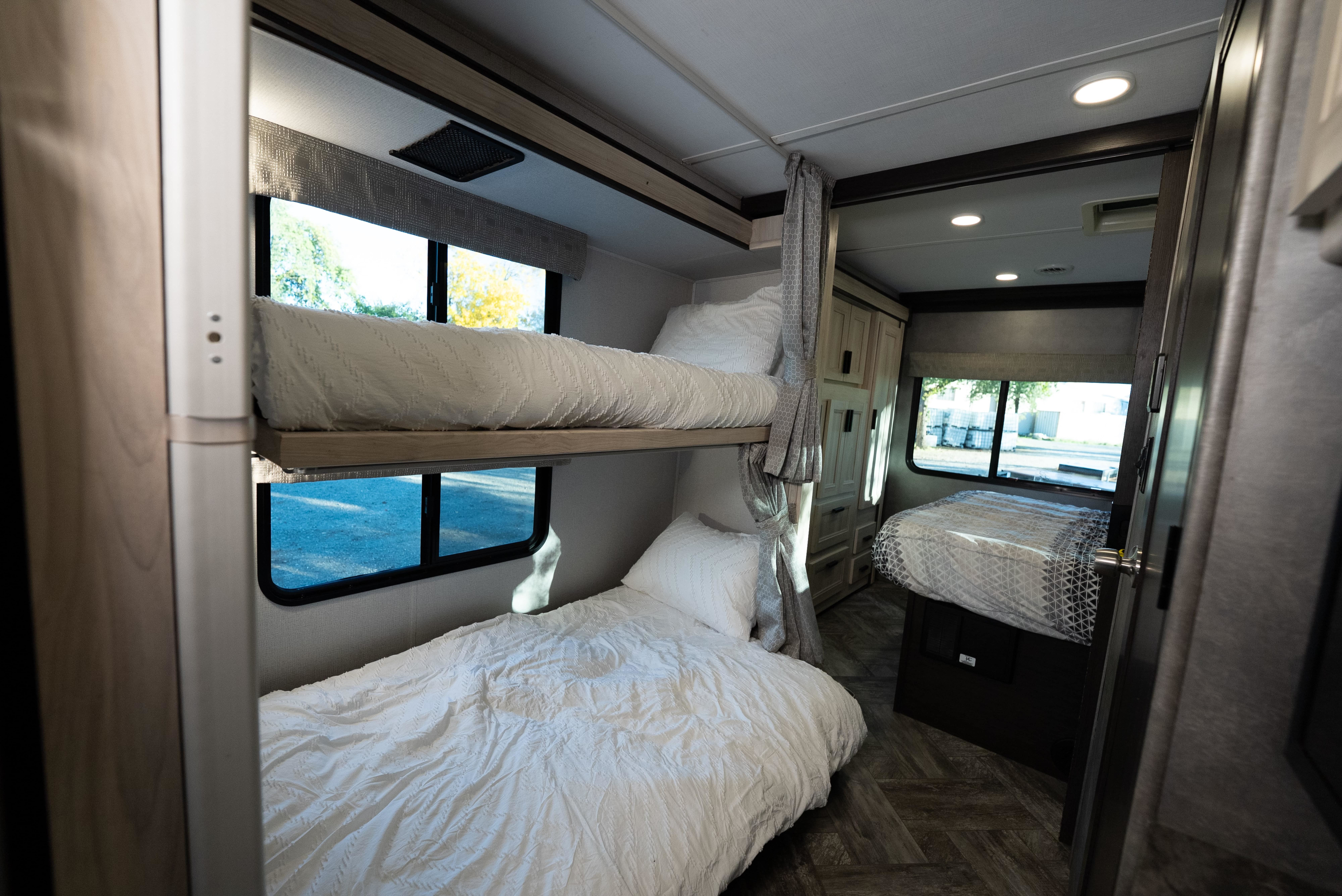 Spacious RV rental interior with cozy bunk beds and a separate bedroom, perfect for family travel and adventure.. Forest River Sunseeker LE 2022