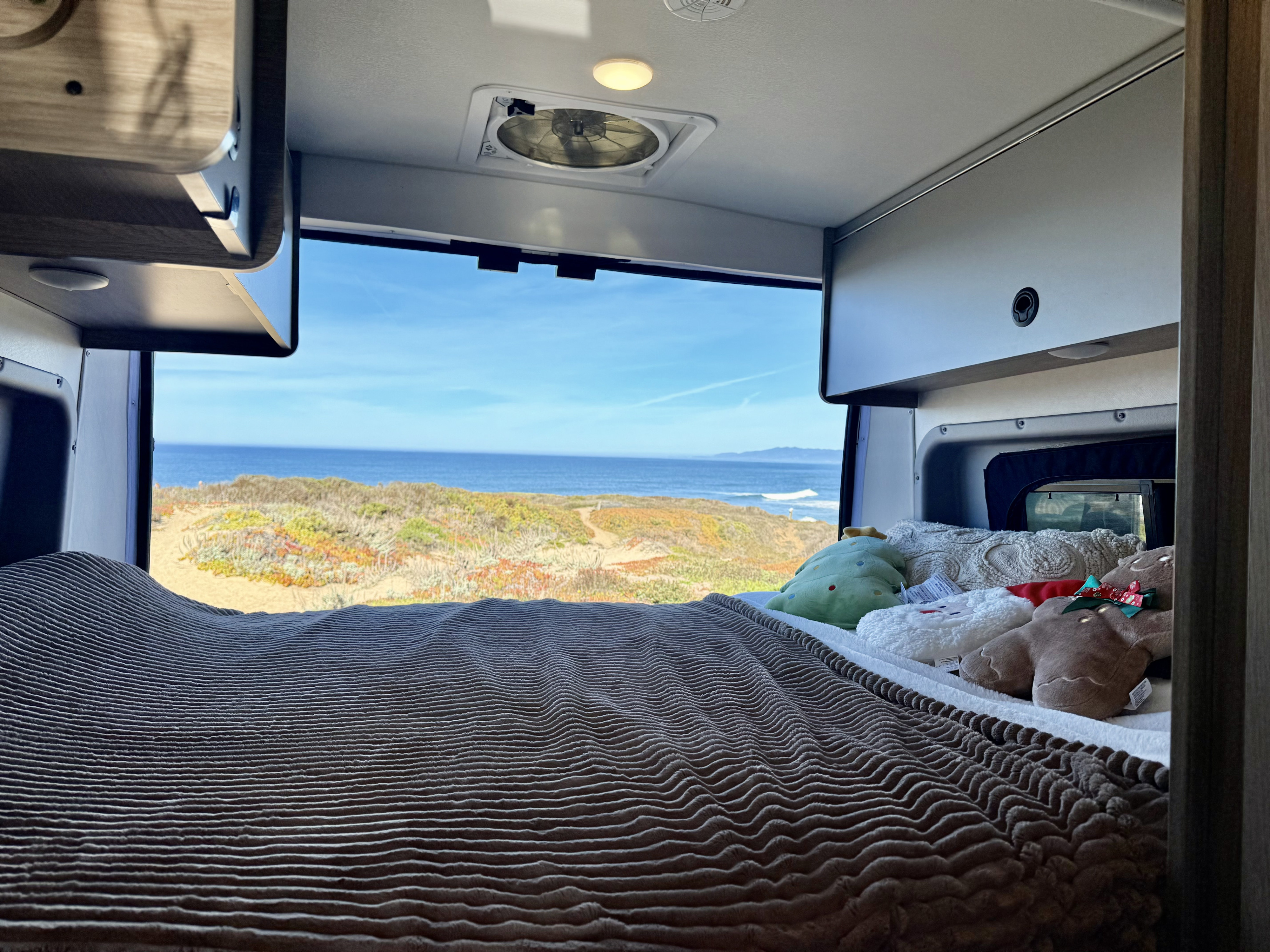 Enjoy an ocean view from your cozy RV rental bed, complete with soft blankets and fun plush toys. Ideal for a coastal retreat.. Winnebago Solis 2022