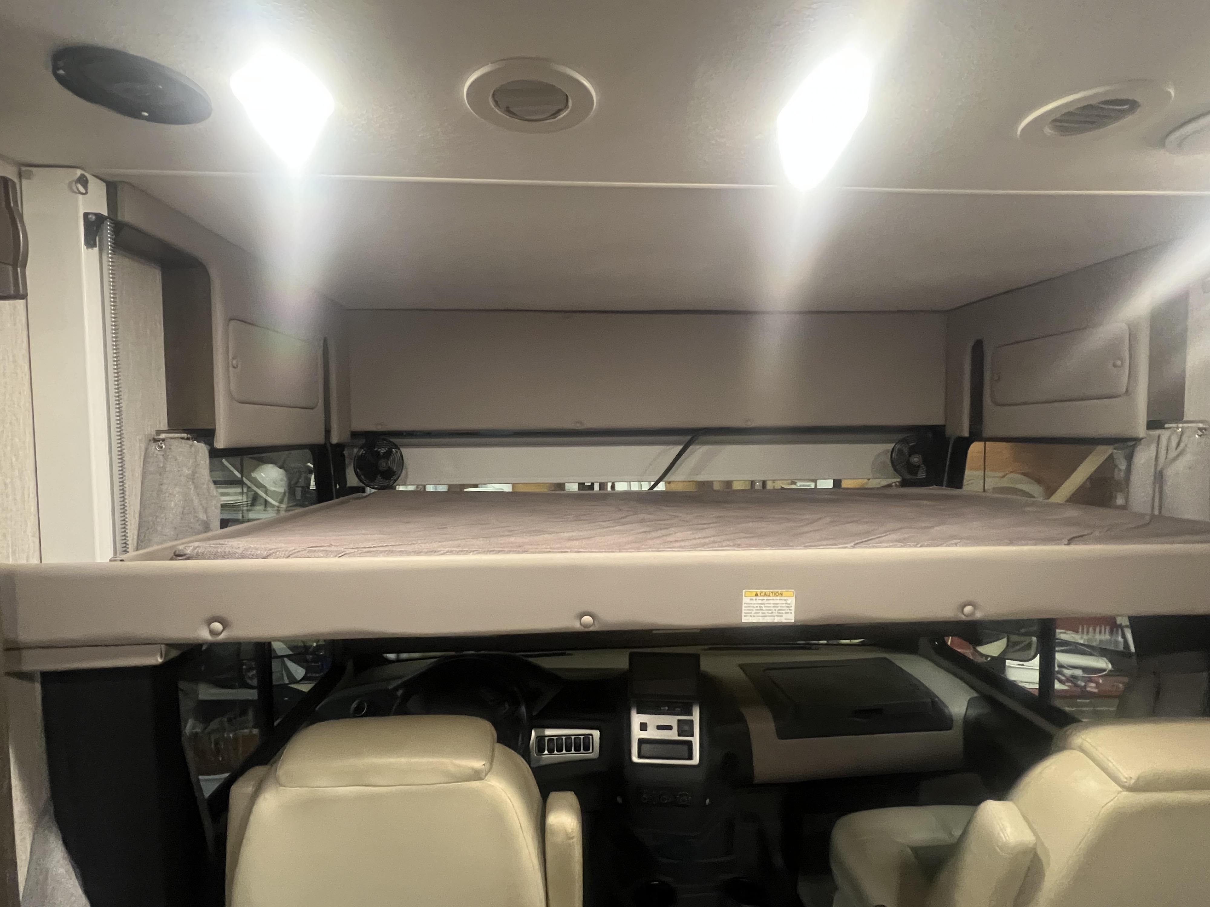 Overhead bunk with mattress in an RV rental, positioned above the driver's cockpit and front seats.. Forest River Coachmen Mirada 2022