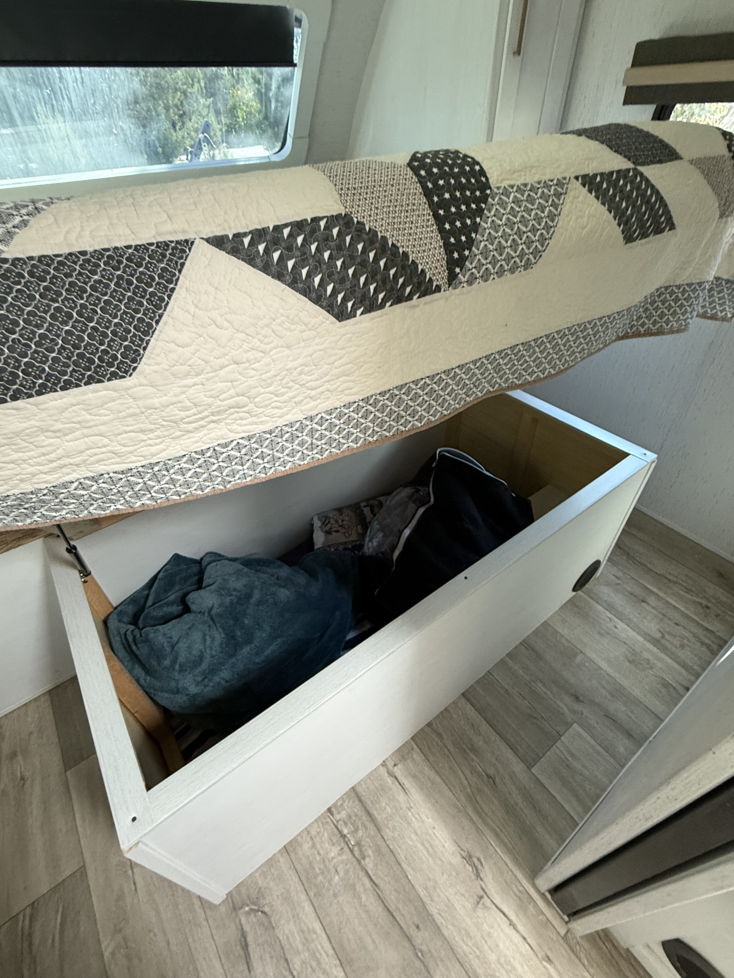 RV rental: Lifted bed reveals under-bed storage with blankets, maximizing space in this cozy RV interior.. Astoria Astoria Trailer 2022