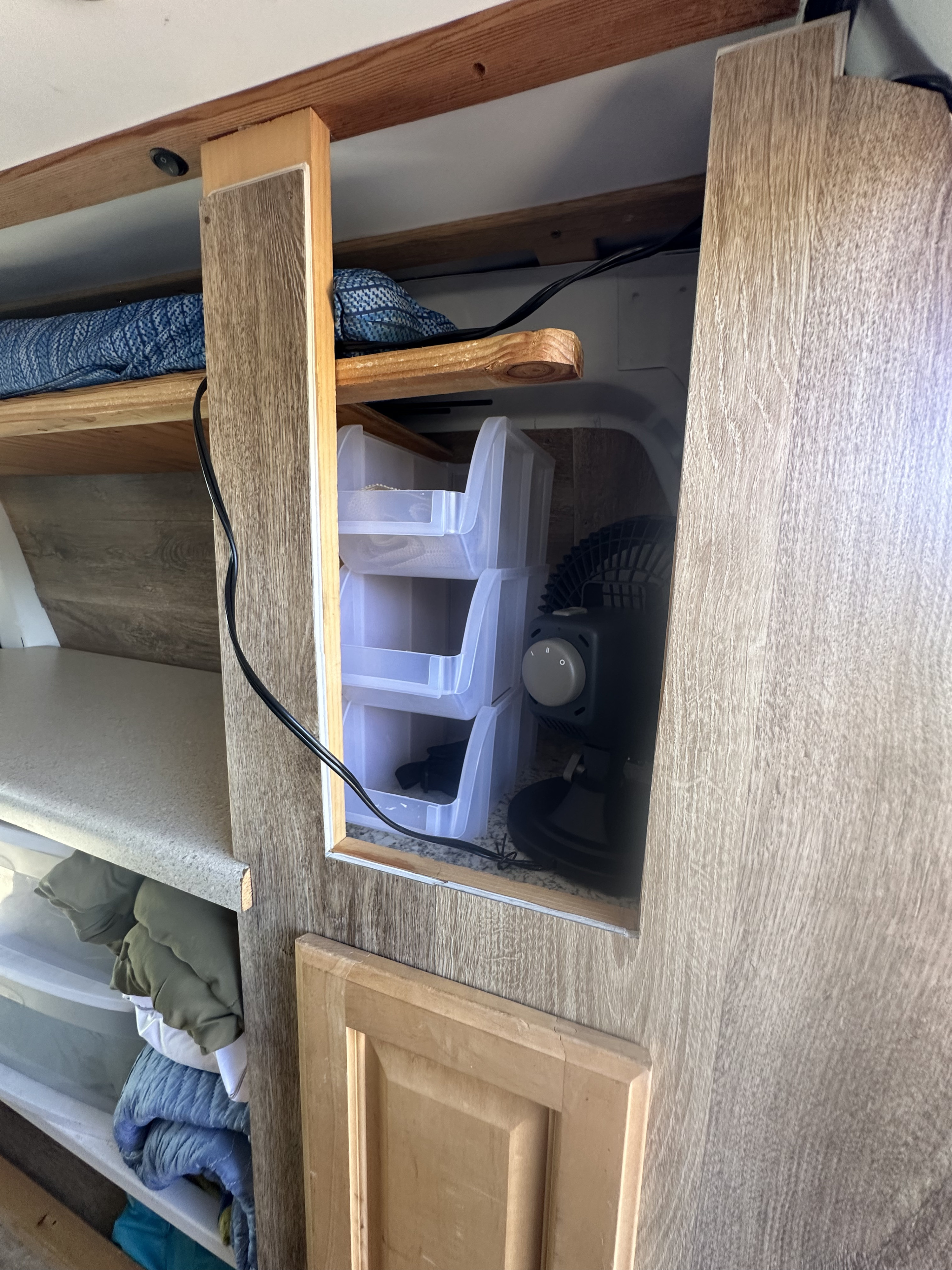 RV rental interior with built-in shelving, plastic storage bins, a fan, and a power cable for organized travel.. Ford Econoline 150 2005