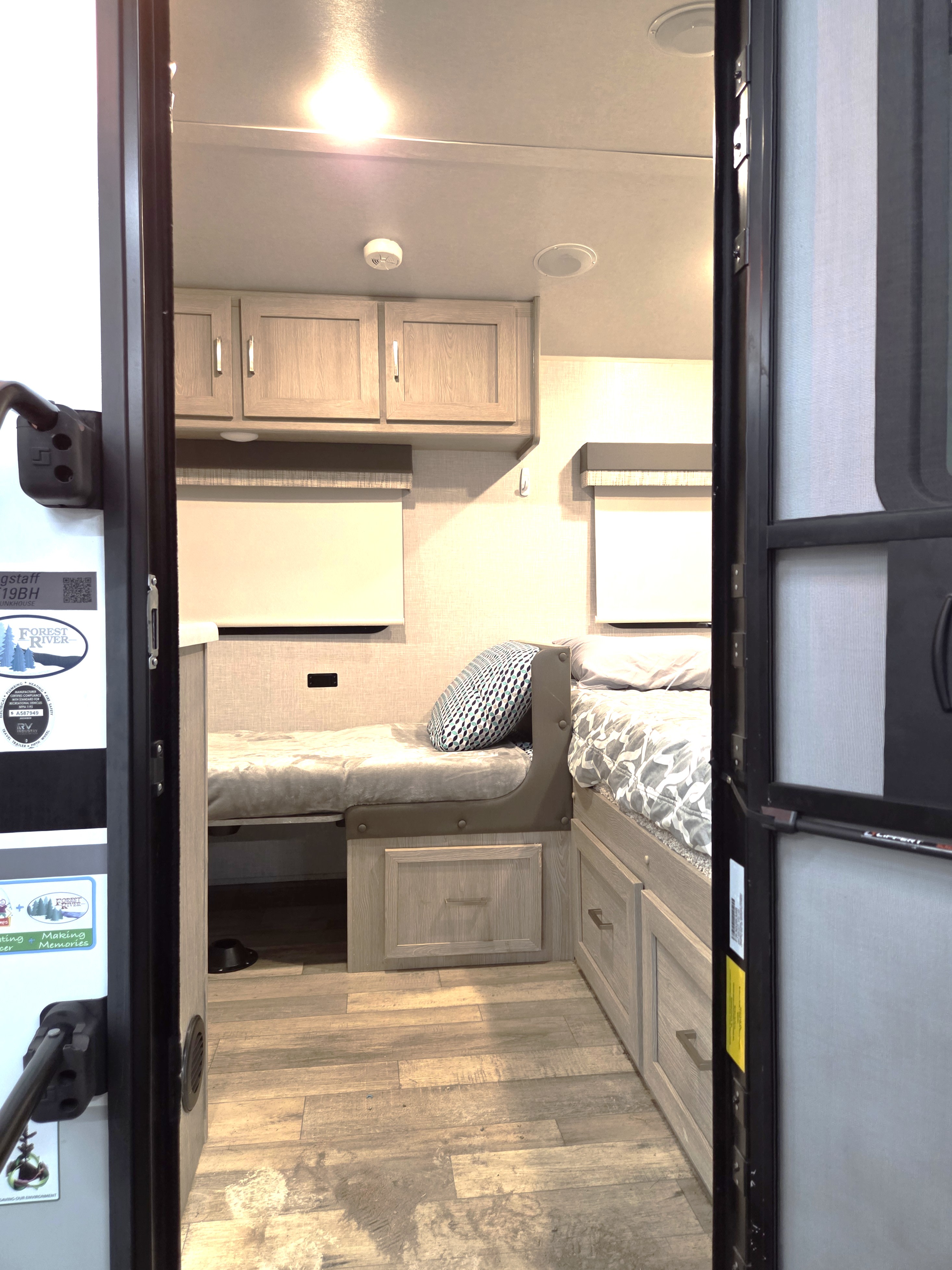 Step into this RV rental bunkhouse, featuring cozy beds, built-in storage, and overhead cabinets, visible from the entry.. Forest River Flagstaff E-Pro 2022