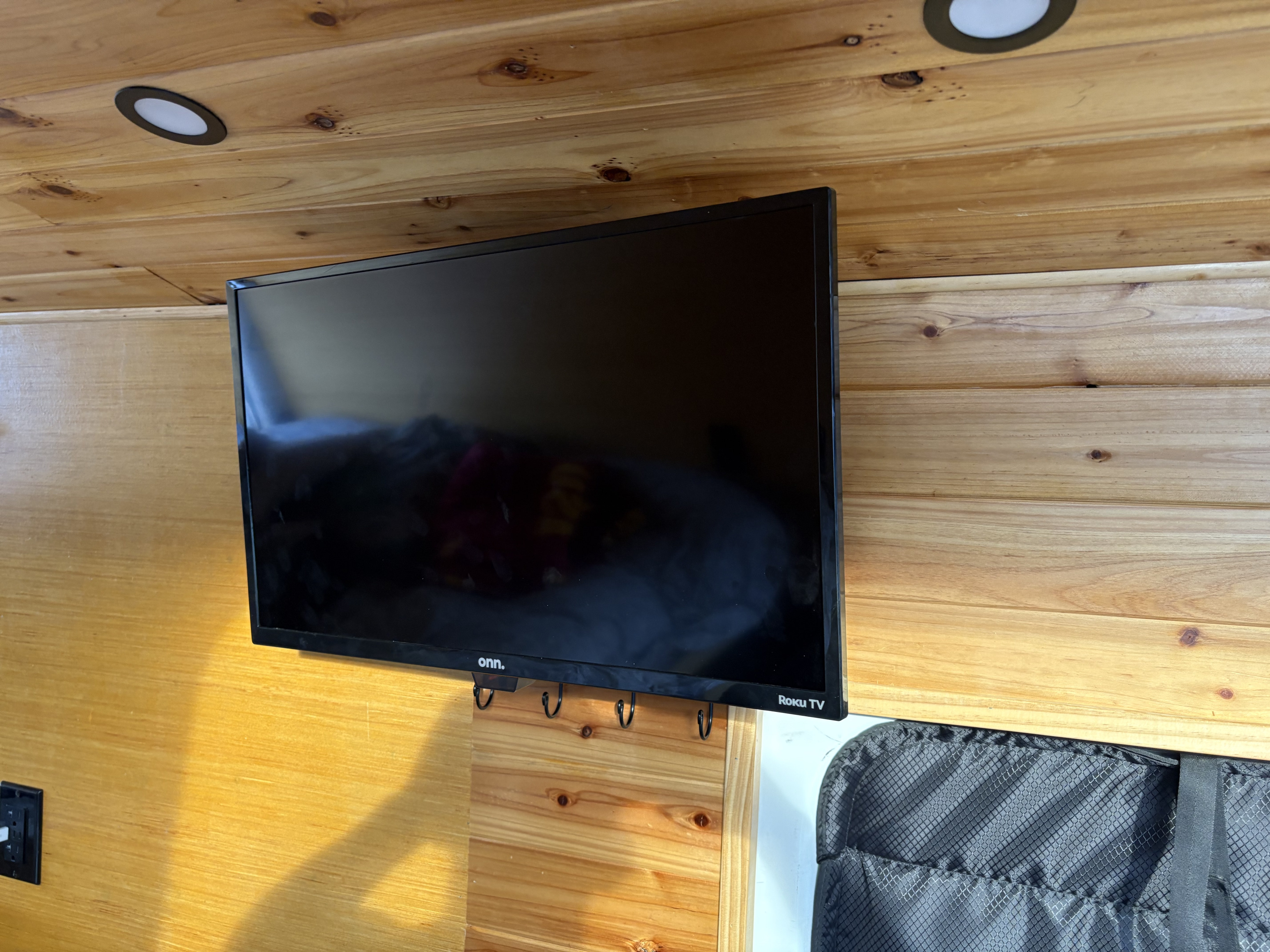 A cozy RV rental interior with a wall-mounted TV on wood-paneled walls and ceiling, plus task lighting.. Mercedes Sprinter 2010