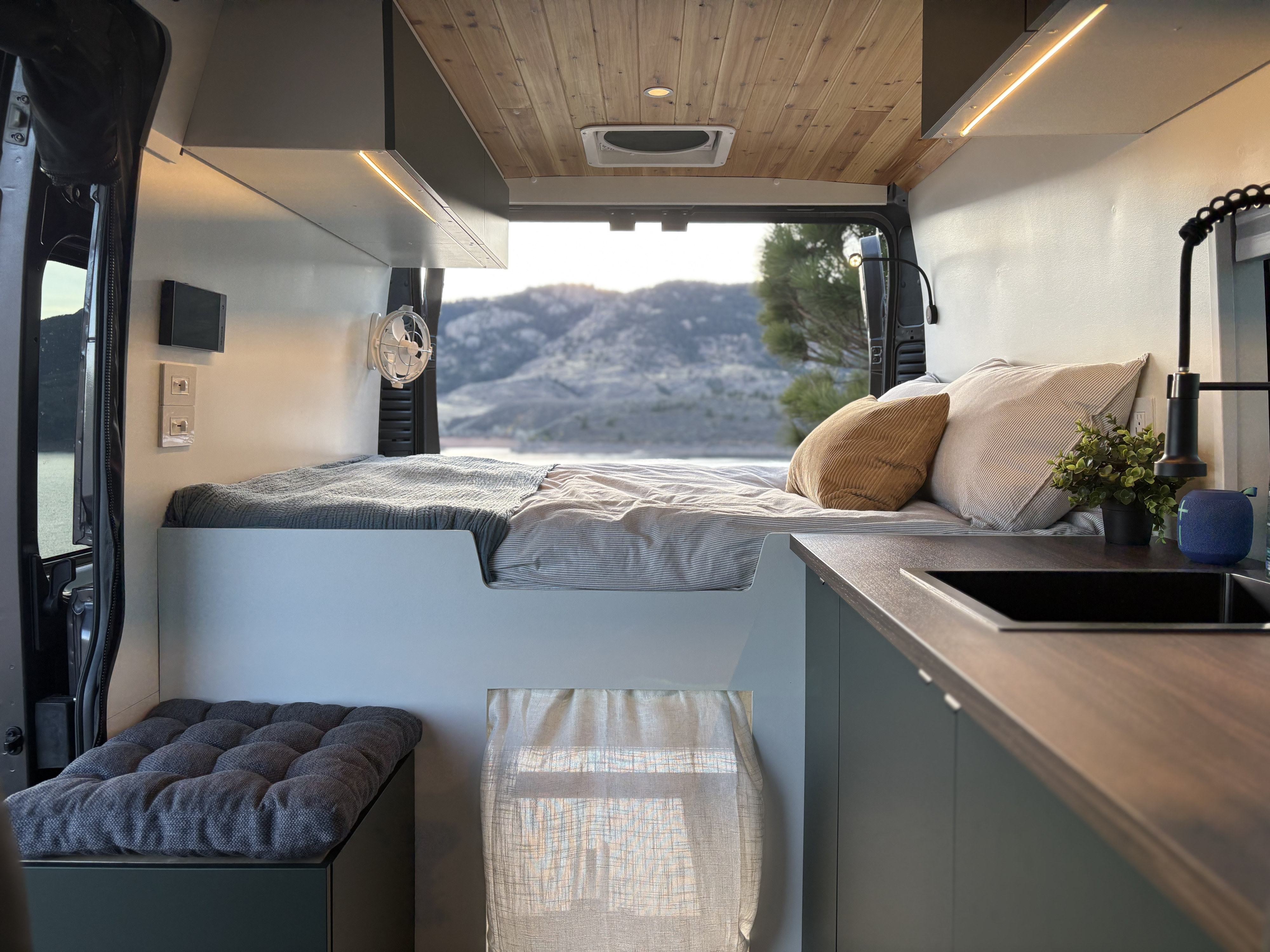 This stylish RV rental offers a modern camper van interior with a cozy bed, kitchen area, and scenic views.. Ram Promaster 2019