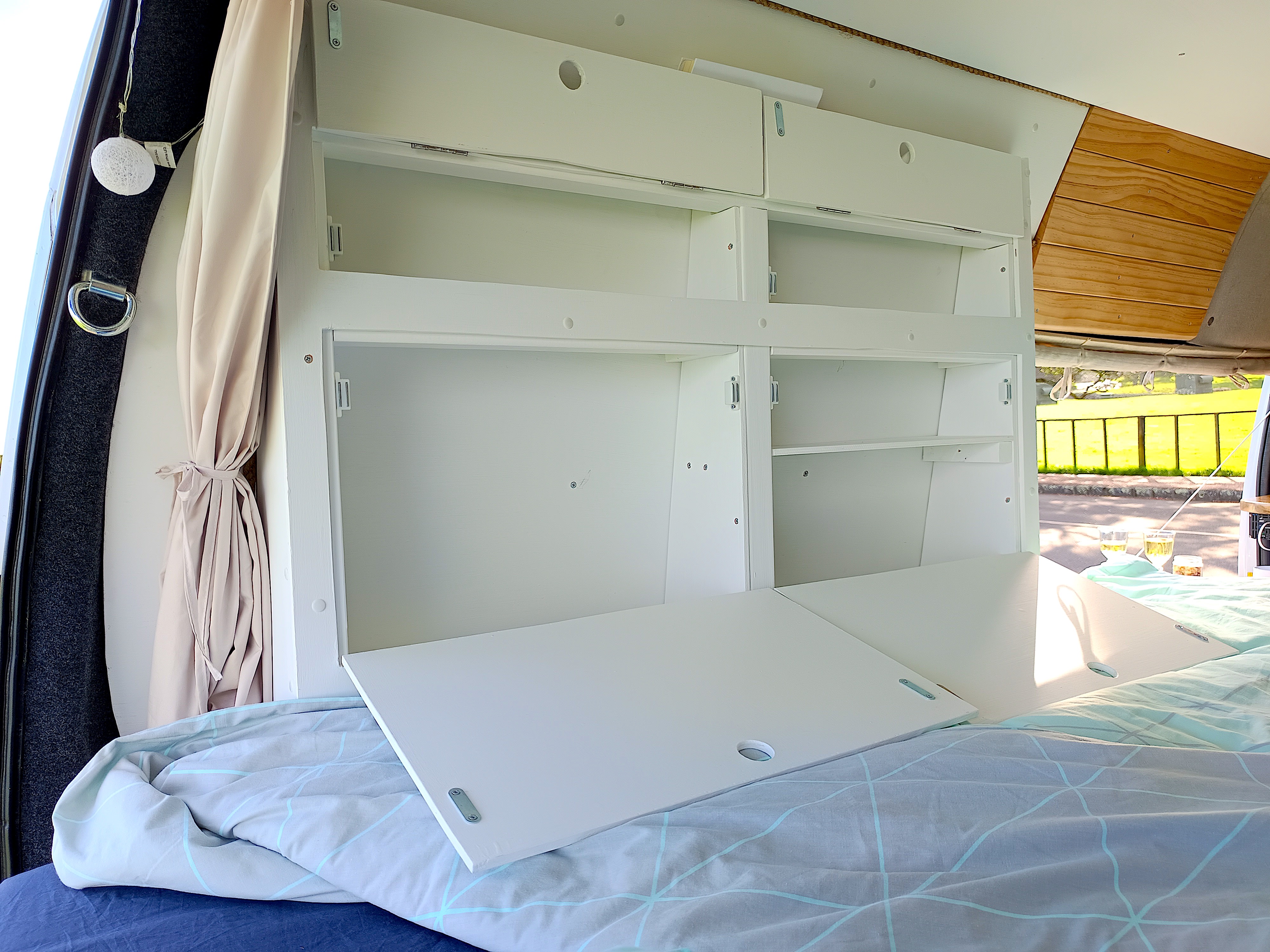 RV rental's custom white cabinetry opens to a bed-side desk/table. Cozy interior with ample storage for your journey.. Toyota Hiace 2005