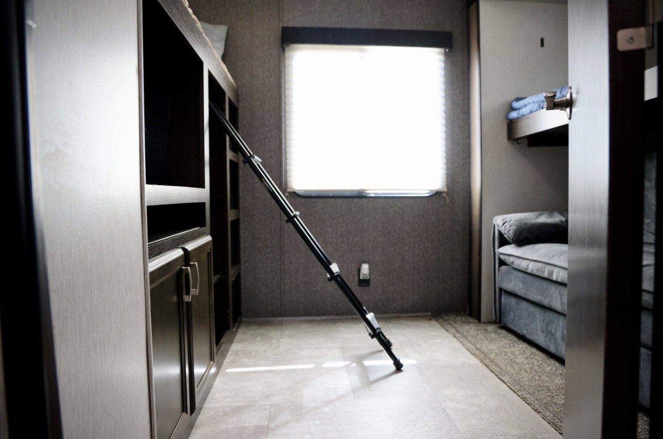 RV rental's bunk room, featuring a ladder, built-in storage, a bright window, and a sofa. Practical camper interior.. Heartland RVs Pioneer 2019