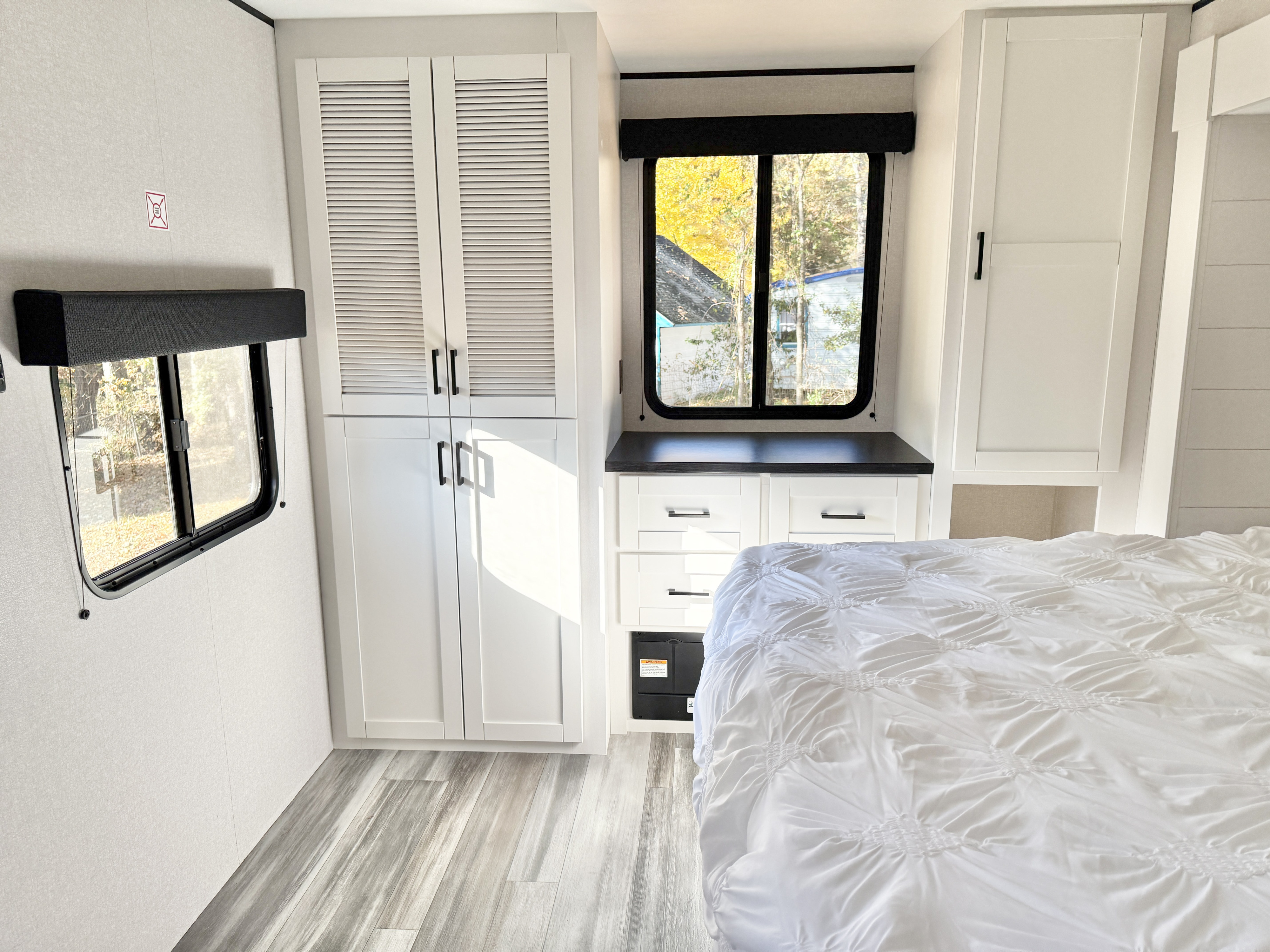 Modern RV rental bedroom interior: crisp white bedding, sleek cabinetry, and large windows with autumn views. Ideal for travel.. Jayco Jay Flight SLX 380DQS 2026