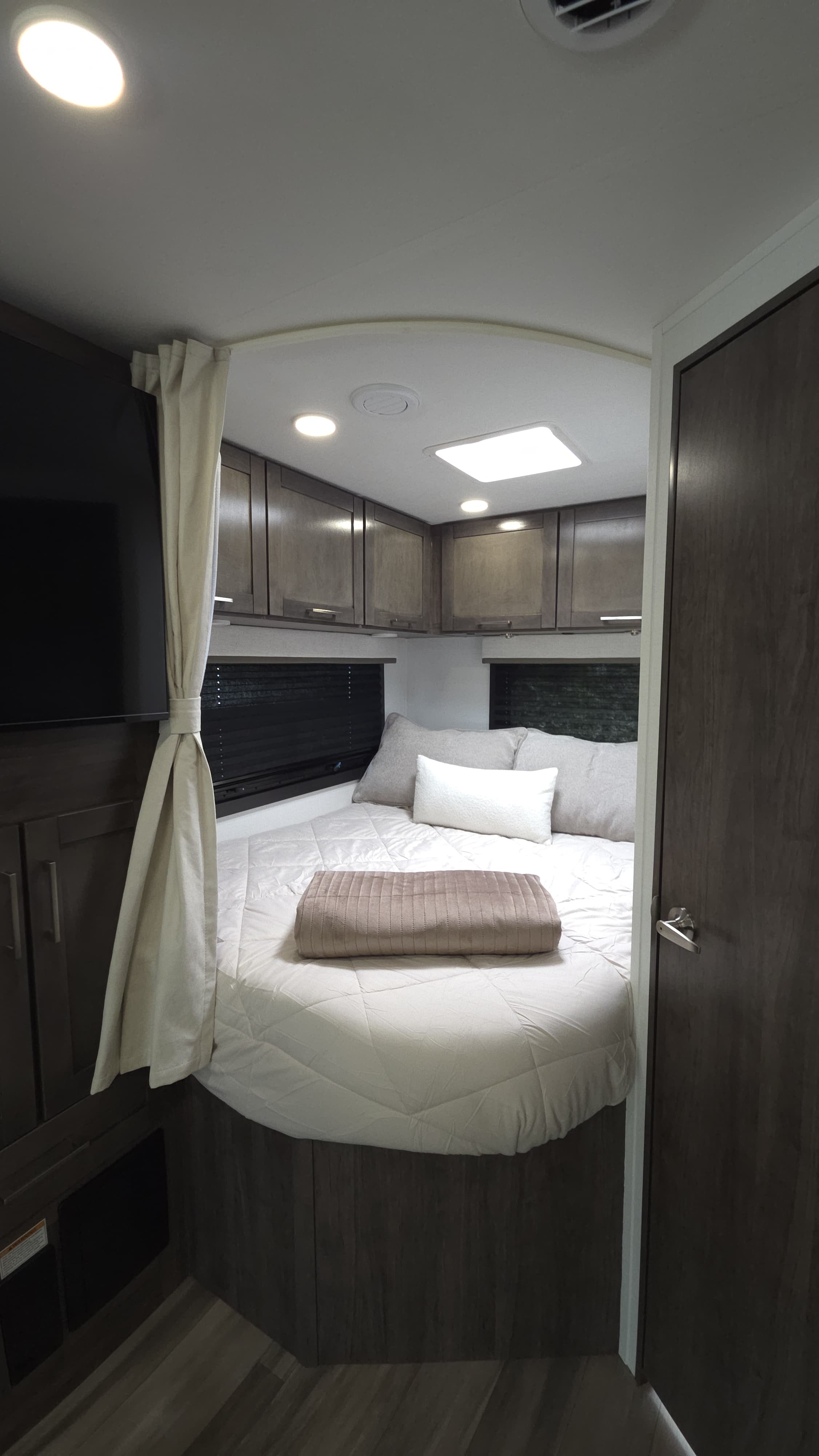 Comfortable RV rental bedroom: queen bed, dark wood cabinets, TV, and recessed lighting for your journey.. Entegra Coach Odyssey 25R 2026