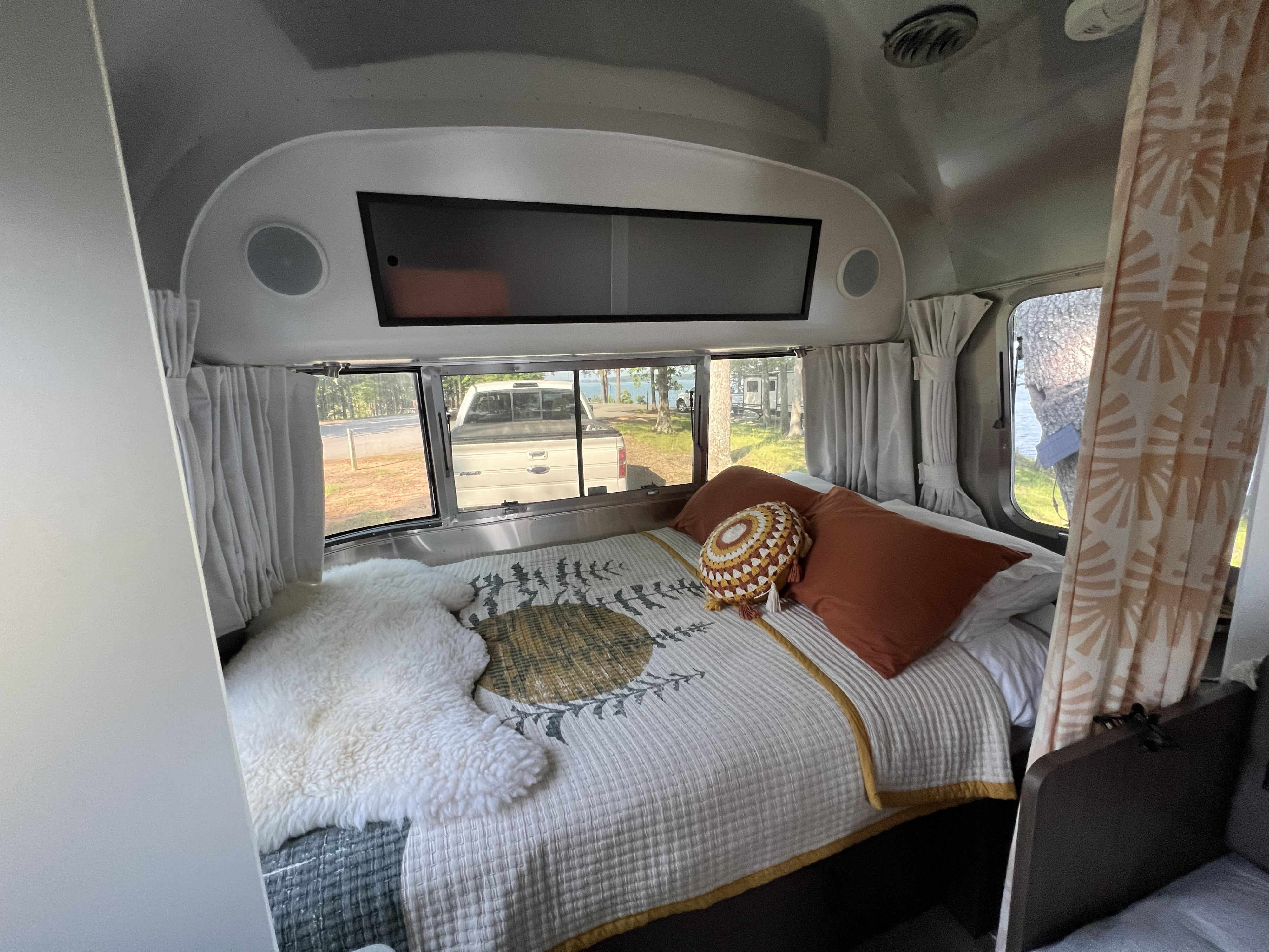 Cozy Airstream rv rental bedroom with a comfortable bed, warm quilt, and scenic window view for your travel adventure.. Airstream Caravel 2020