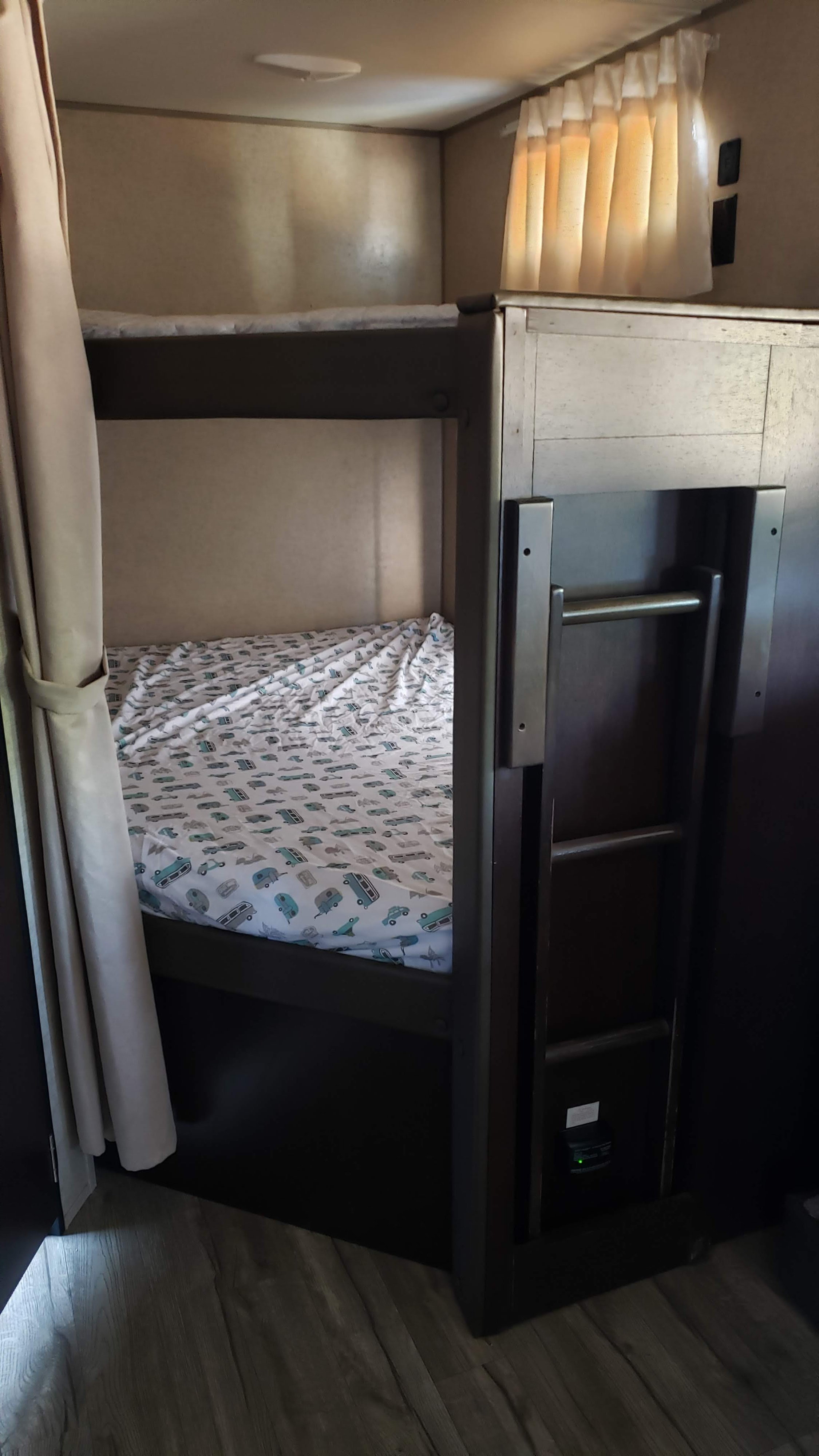 Inside an RV rental: a cozy bunk bed setup with a fun vehicle-themed sheet and ladder access.. Forest River Cherokee Grey Wolf 2017