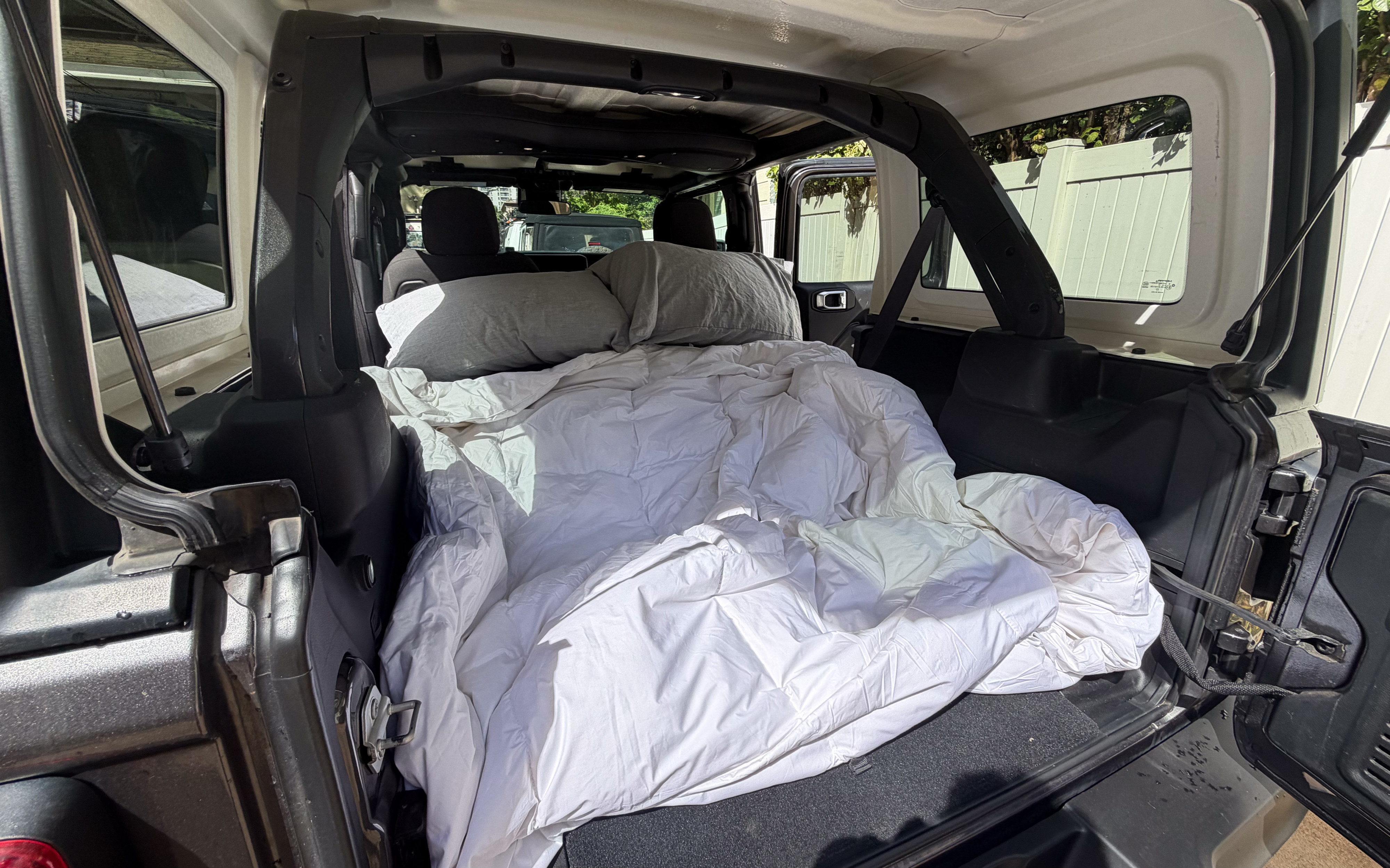 Cozy car camping setup in a Jeep, perfect for your next RV rental adventure. Pillows & comforter ready for an overnight stay.. Jeep Wrangler Rubicon 2024