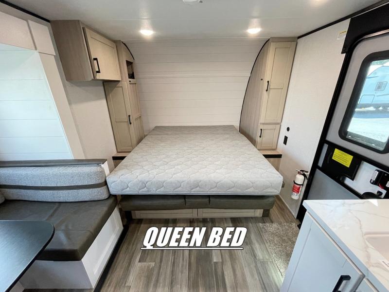 RV rental interior featuring a comfortable queen bed, dining area, storage cabinets, and a small kitchen counter.. Open Range Colt MBS 18 2026