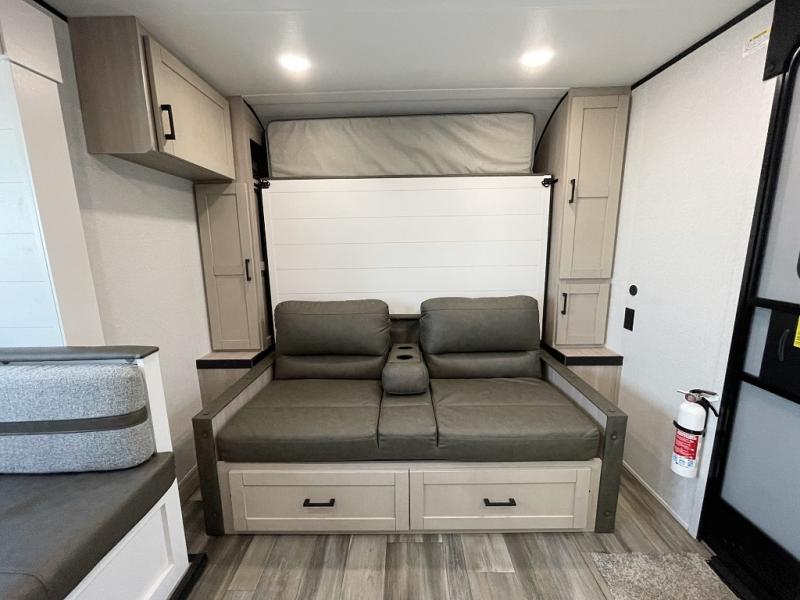 This RV rental interior features a cozy sofa with storage, cabinets, and a hidden Murphy bed above, offering versatile living space.. Open Range Colt MBS 18 2026
