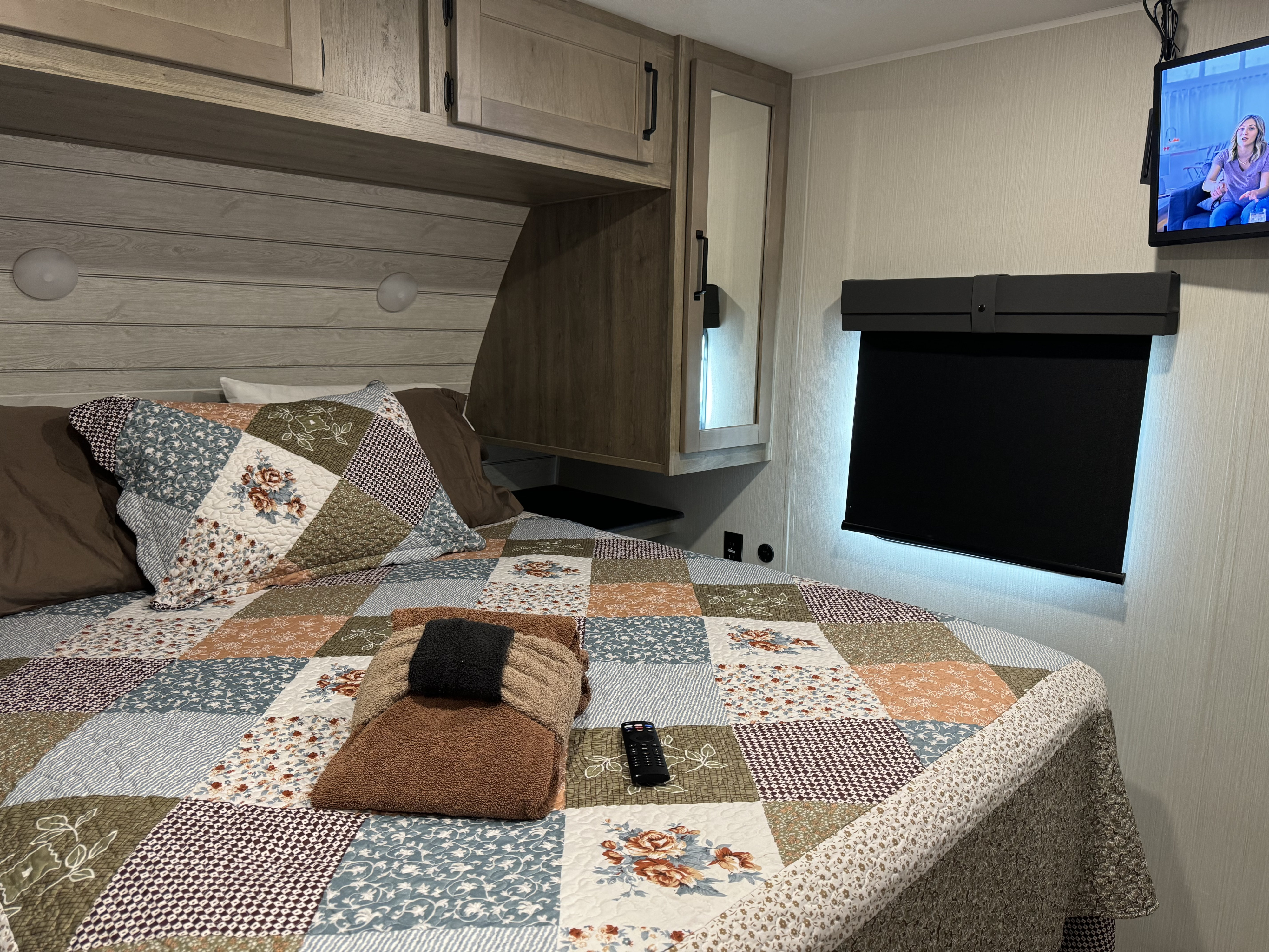 Cozy RV rental bedroom with a patchwork quilt, overhead cabinets, TV, and black-out shade, offering a comfortable stay.. Palomino Puma 32BH2B 2024